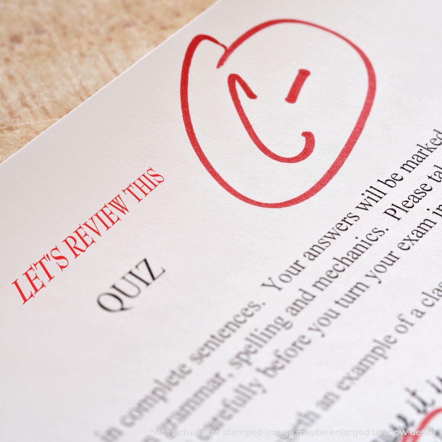 A paper with a red smiley face and the text LET'S REVIEW THIS stamped using the Large Lets Review This Rubber Stamp.