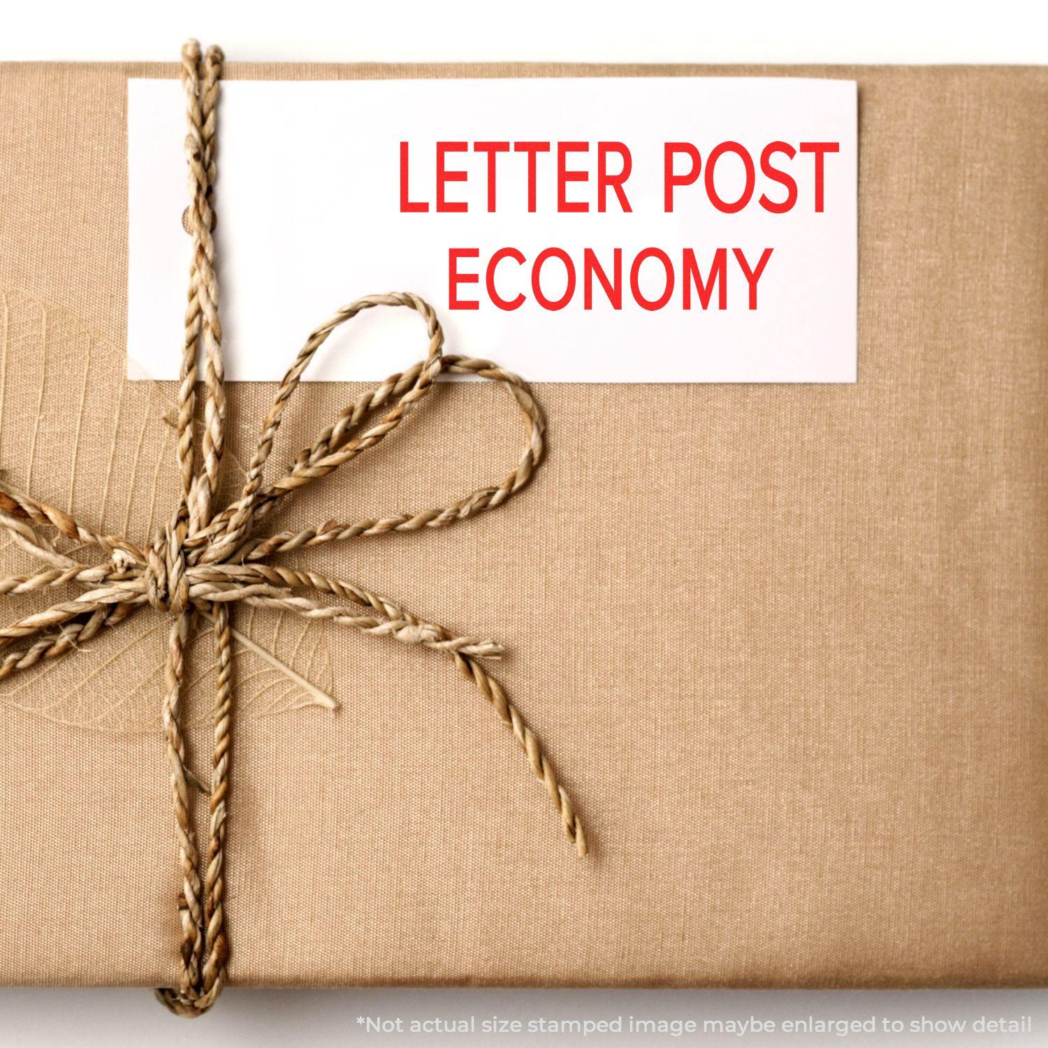 A brown package tied with twine, featuring a red LETTER POST ECONOMY rubber stamp on a white label.