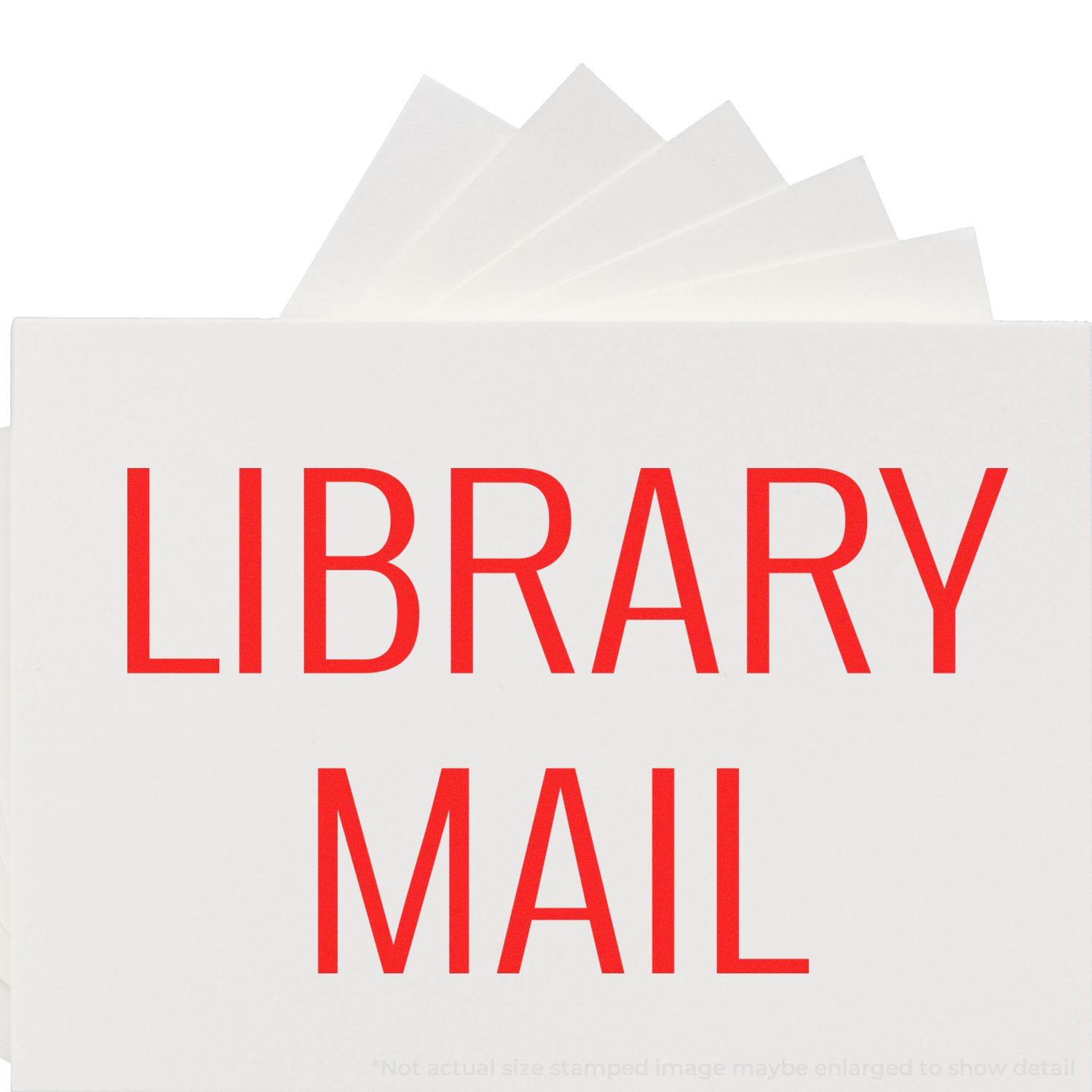 Large Library Mail Rubber Stamp in red ink on white paper, with multiple sheets fanned out behind the stamped text.