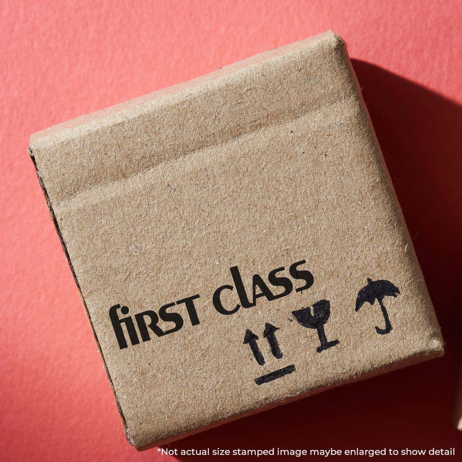 Lower Case First Class Rubber Stamp on a cardboard box with fragile symbols on a red background.