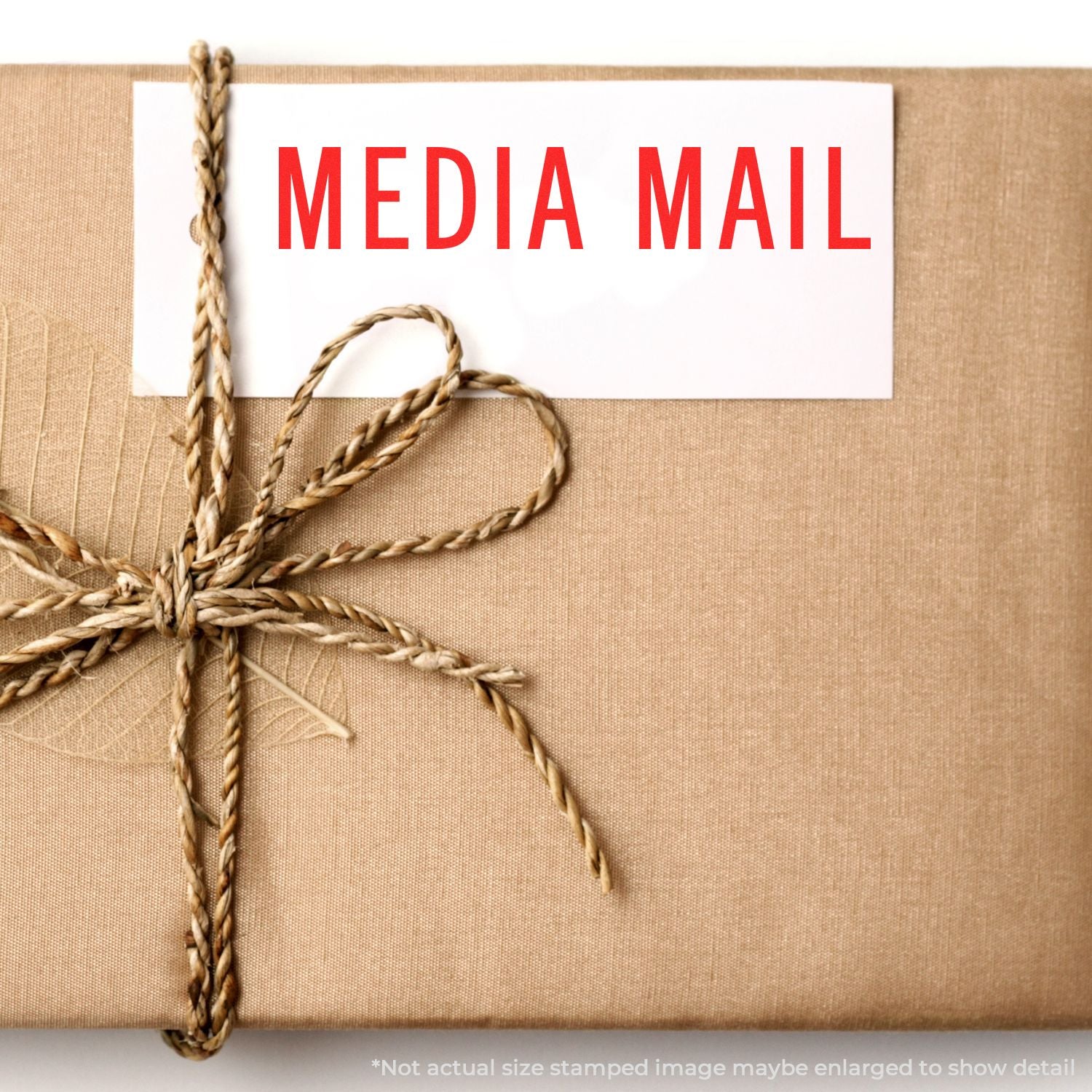 A brown package with a twine bow and a white label stamped MEDIA MAIL using the Self Inking Media Mail Stamp.