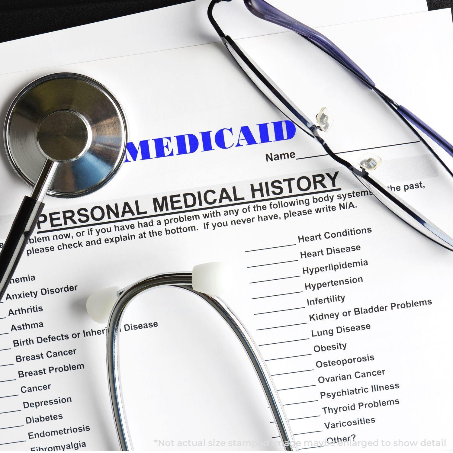 Personal medical history form stamped with MEDICAID using a Large Medicaid Rubber Stamp, surrounded by medical tools like stethoscopes and glasses.