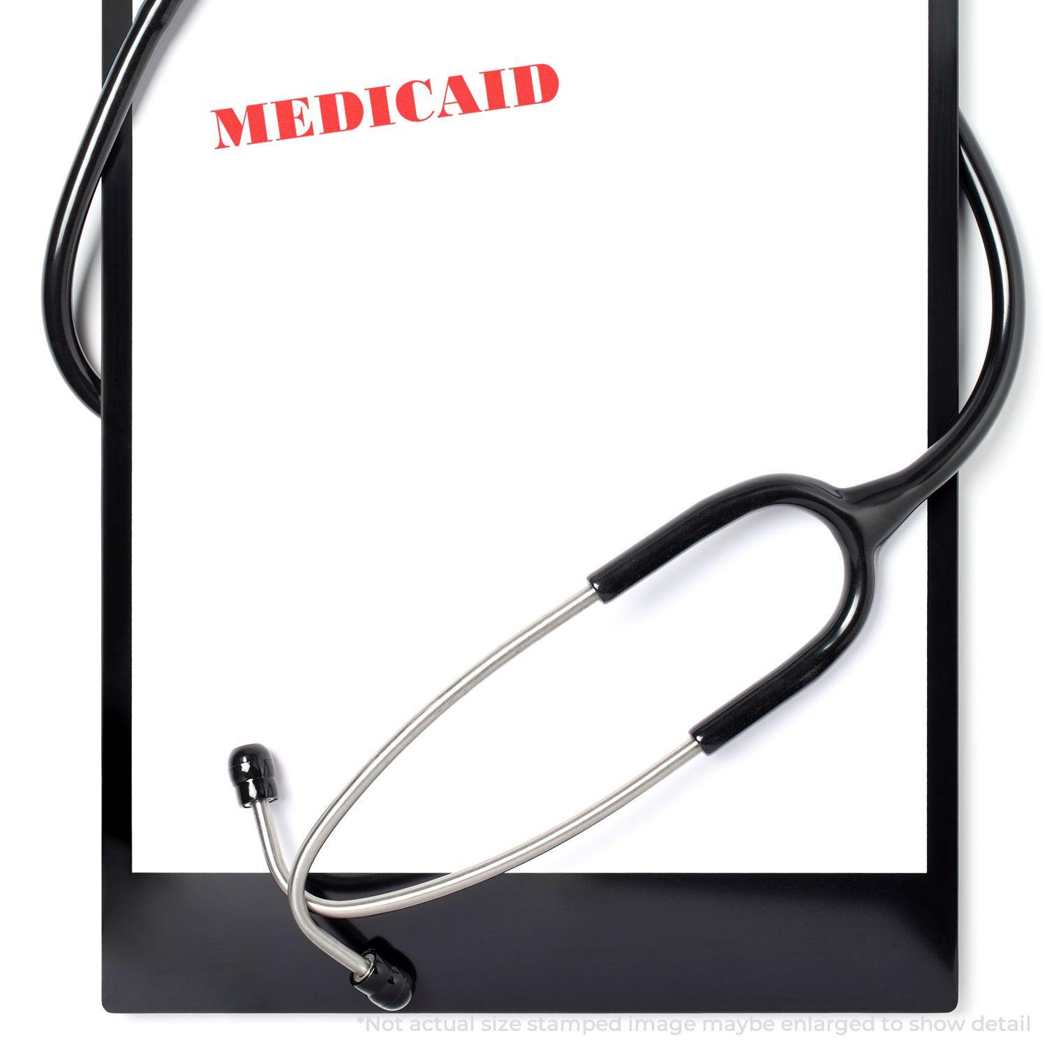 Large Pre-Inked Medicaid Stamp used on a white paper on a clipboard with a stethoscope draped over it.