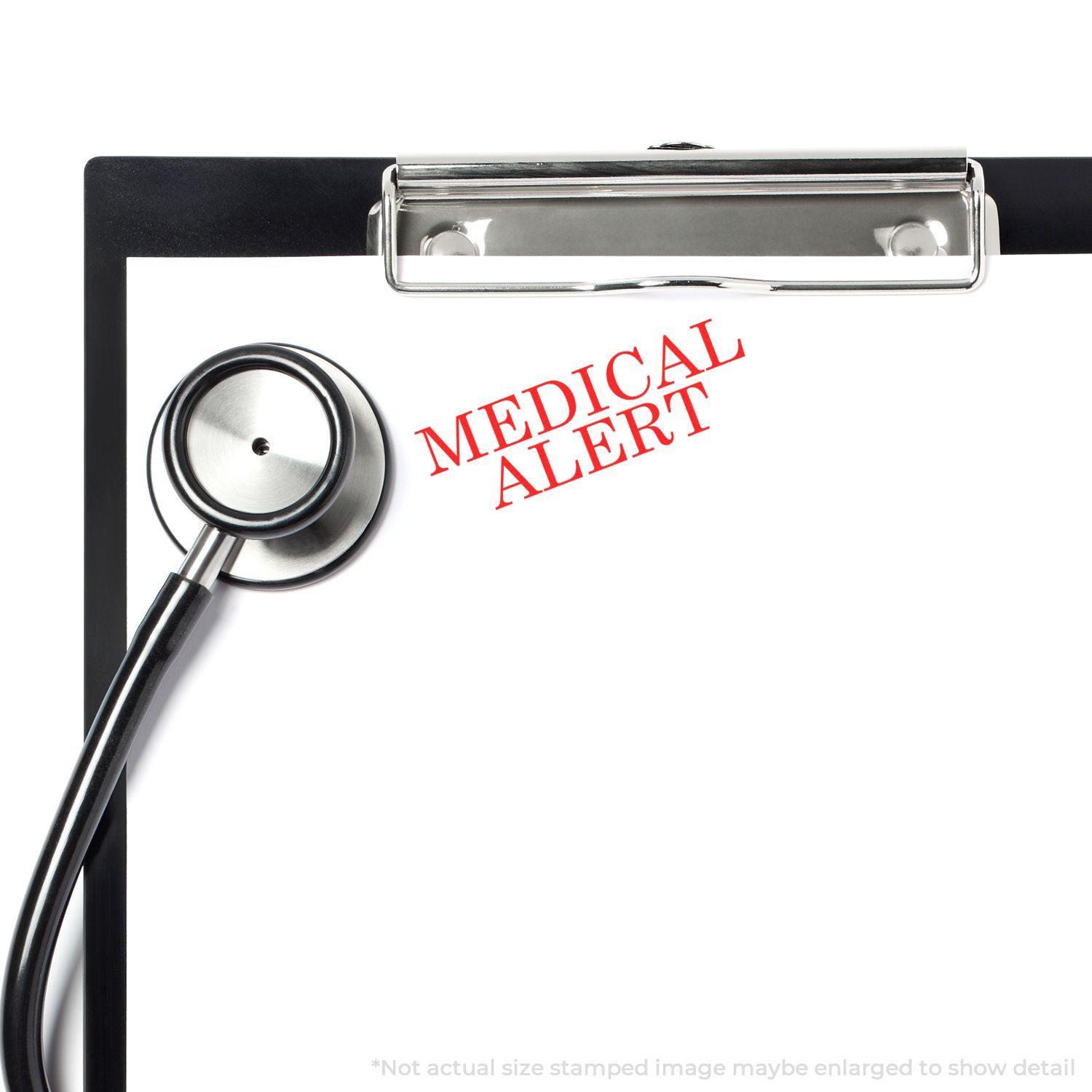 Clipboard with a stethoscope and a Large Self Inking Medical Alert Stamp marking MEDICAL ALERT in red on a blank paper.