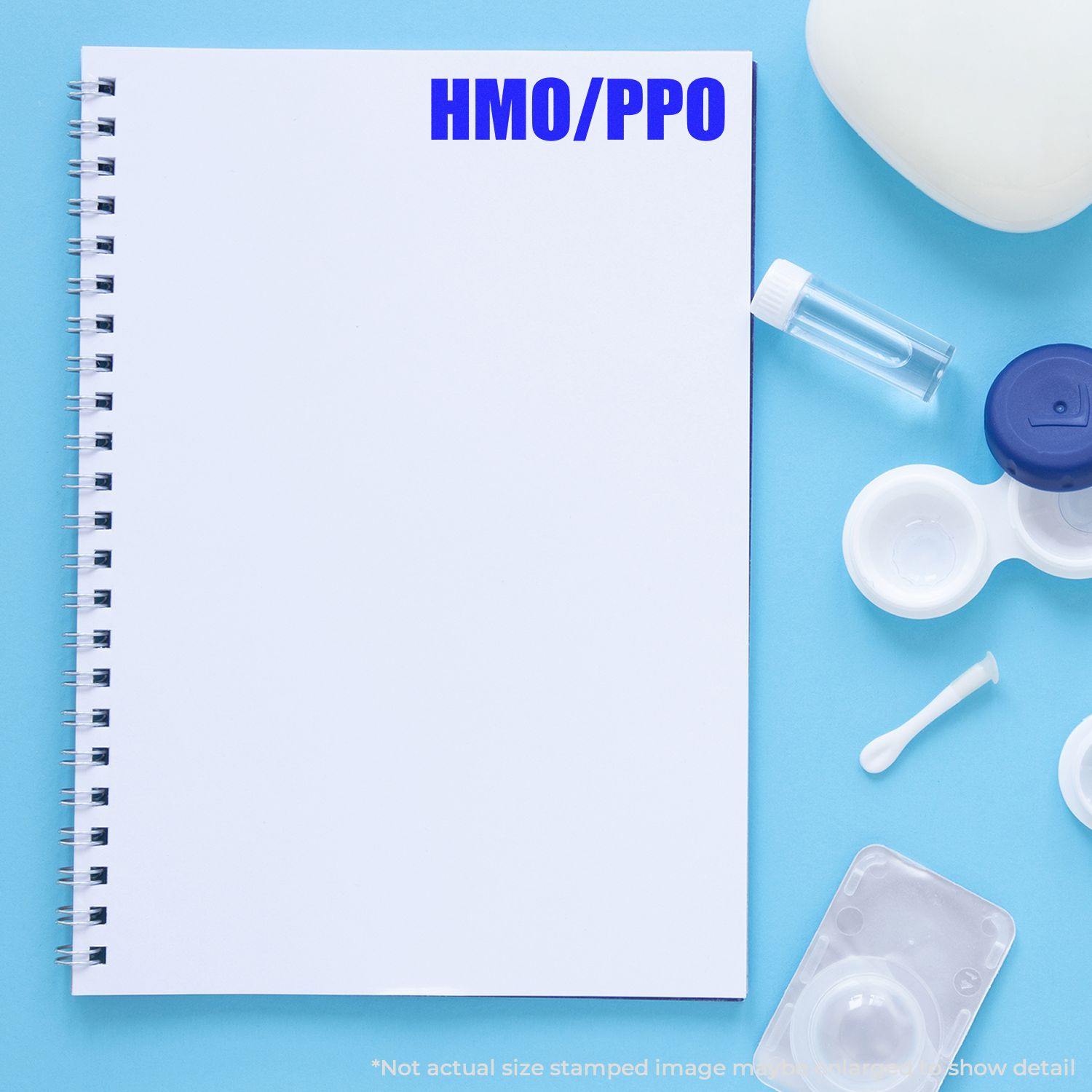 Large HMO/PPO Rubber Stamp used on a blank notebook page, surrounded by medical items on a blue background.