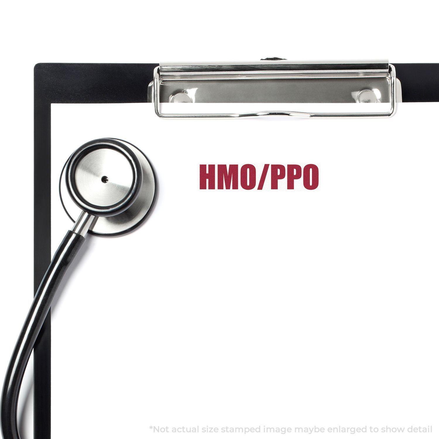 A clipboard with a stethoscope and a paper stamped with HMO/PPO using the Large HMO/PPO Rubber Stamp.