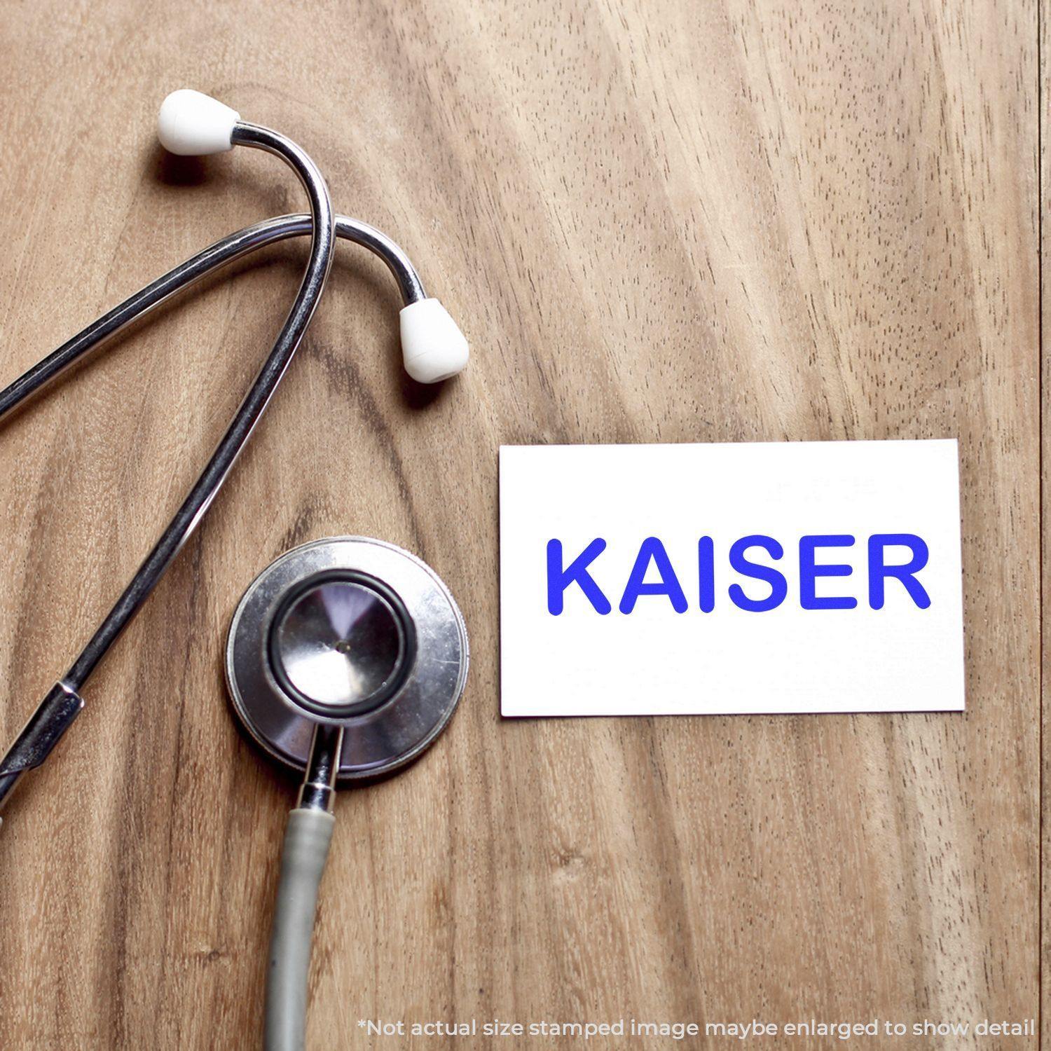 Medical Kaiser rubber stamp on a white card beside a stethoscope on a wooden surface.