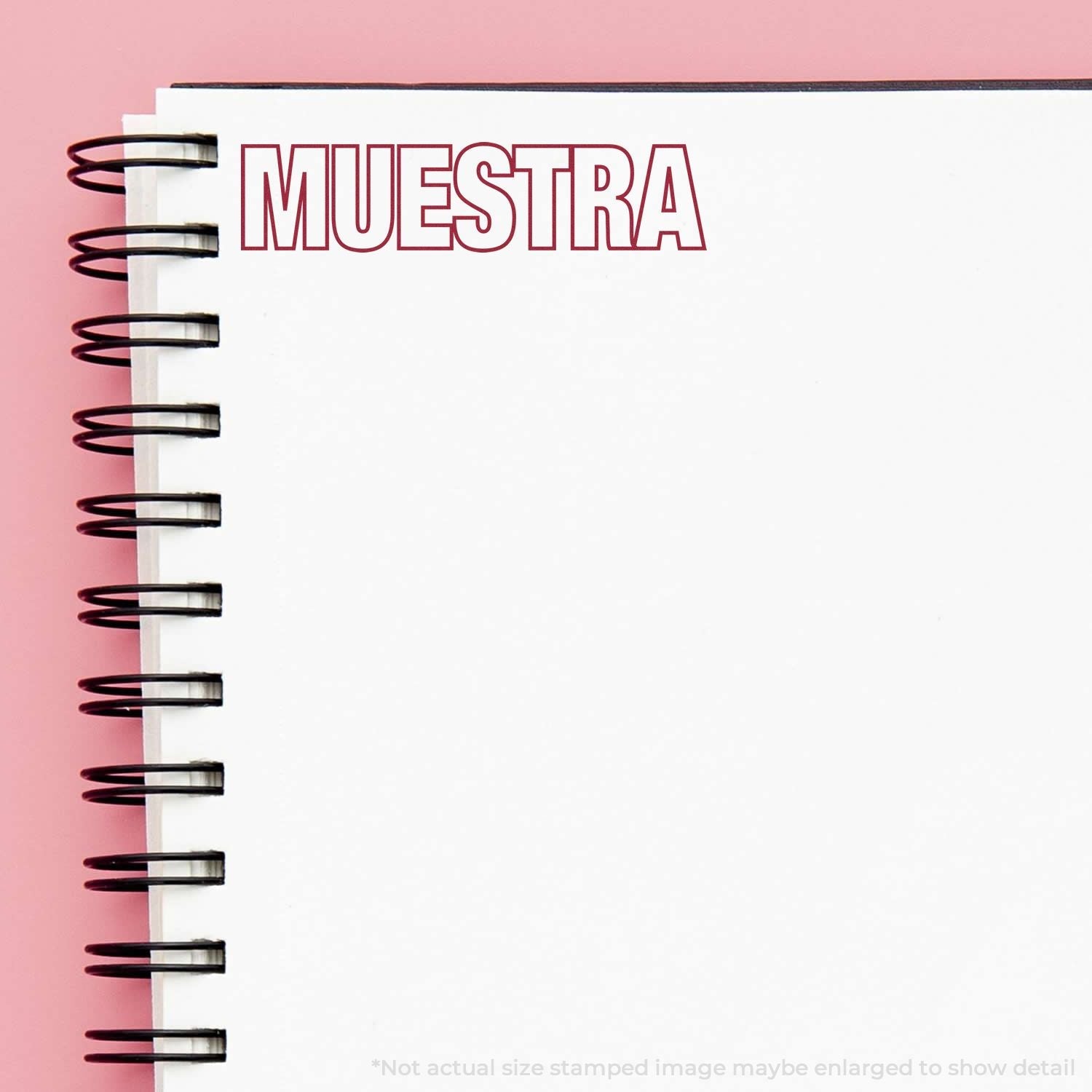 Self Inking Muestra Stamp imprint on a white spiral notebook page with a pink background.