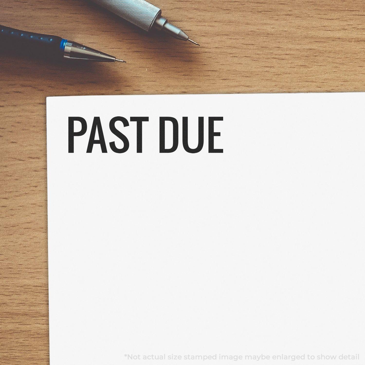 Narrow Bold Past Due rubber stamp on white paper, with a pen and pencil on a wooden desk background.