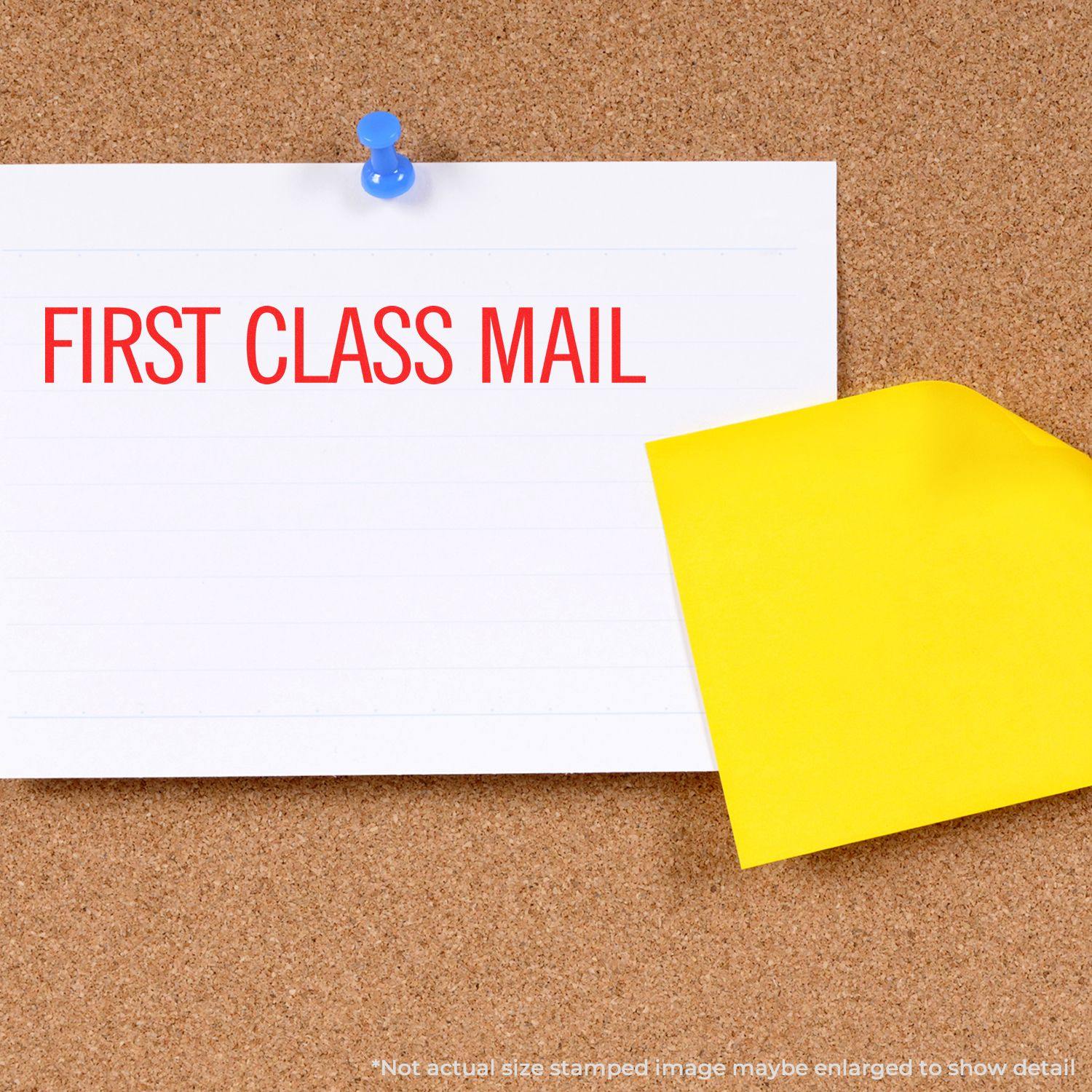 Narrow First Class Mail rubber stamp impression on a white card pinned to a corkboard, with a yellow envelope beside it.