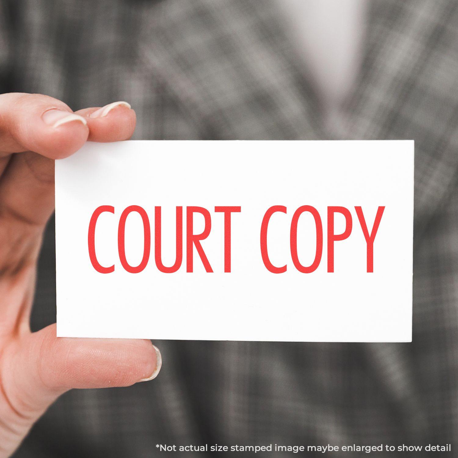 Hand holding a white card with COURT COPY in red narrow font, demonstrating the use of a rubber stamp.