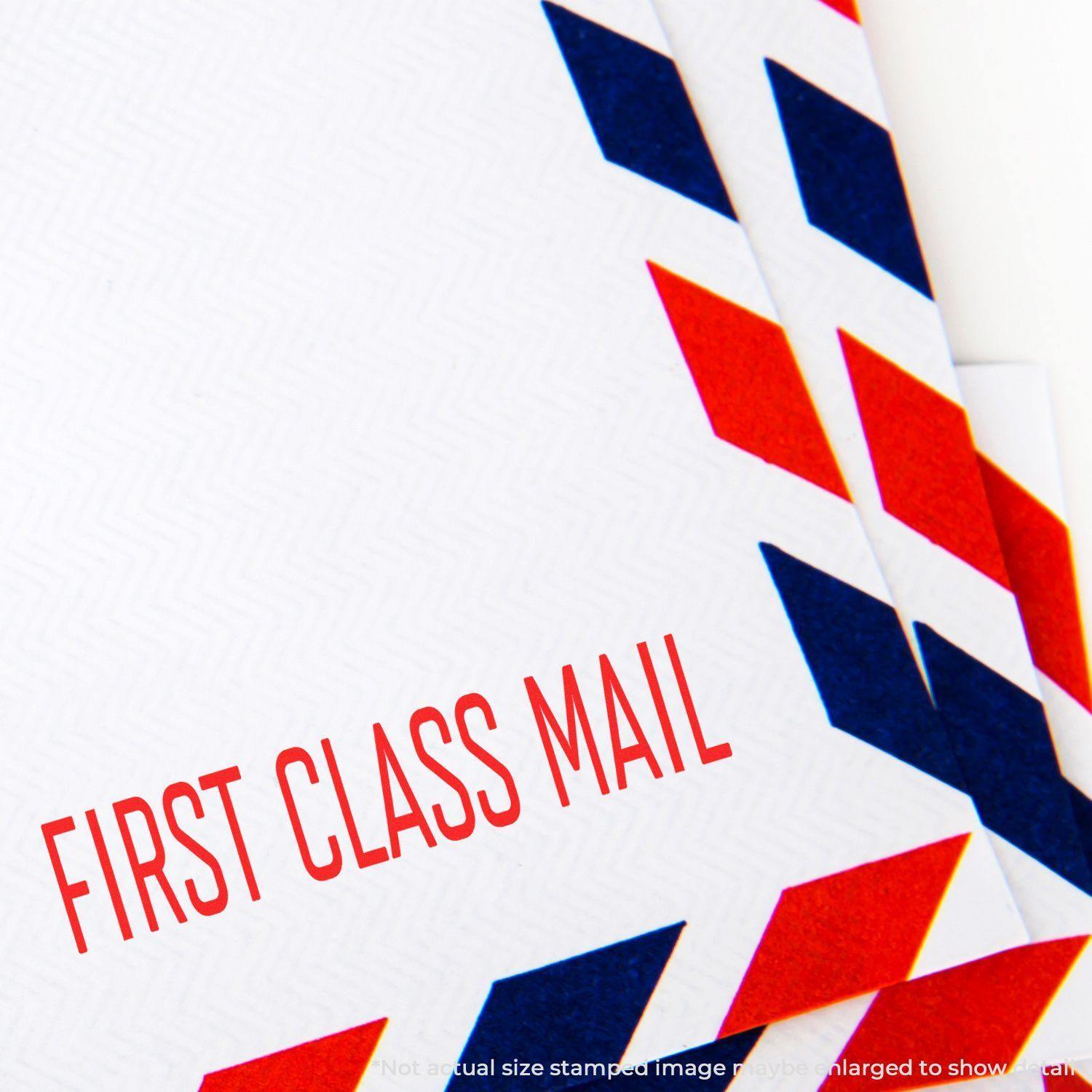 A stock office rubber stamp with a stamped image showing how the text "FIRST CLASS MAIL" in a large narrow font is displayed after stamping.