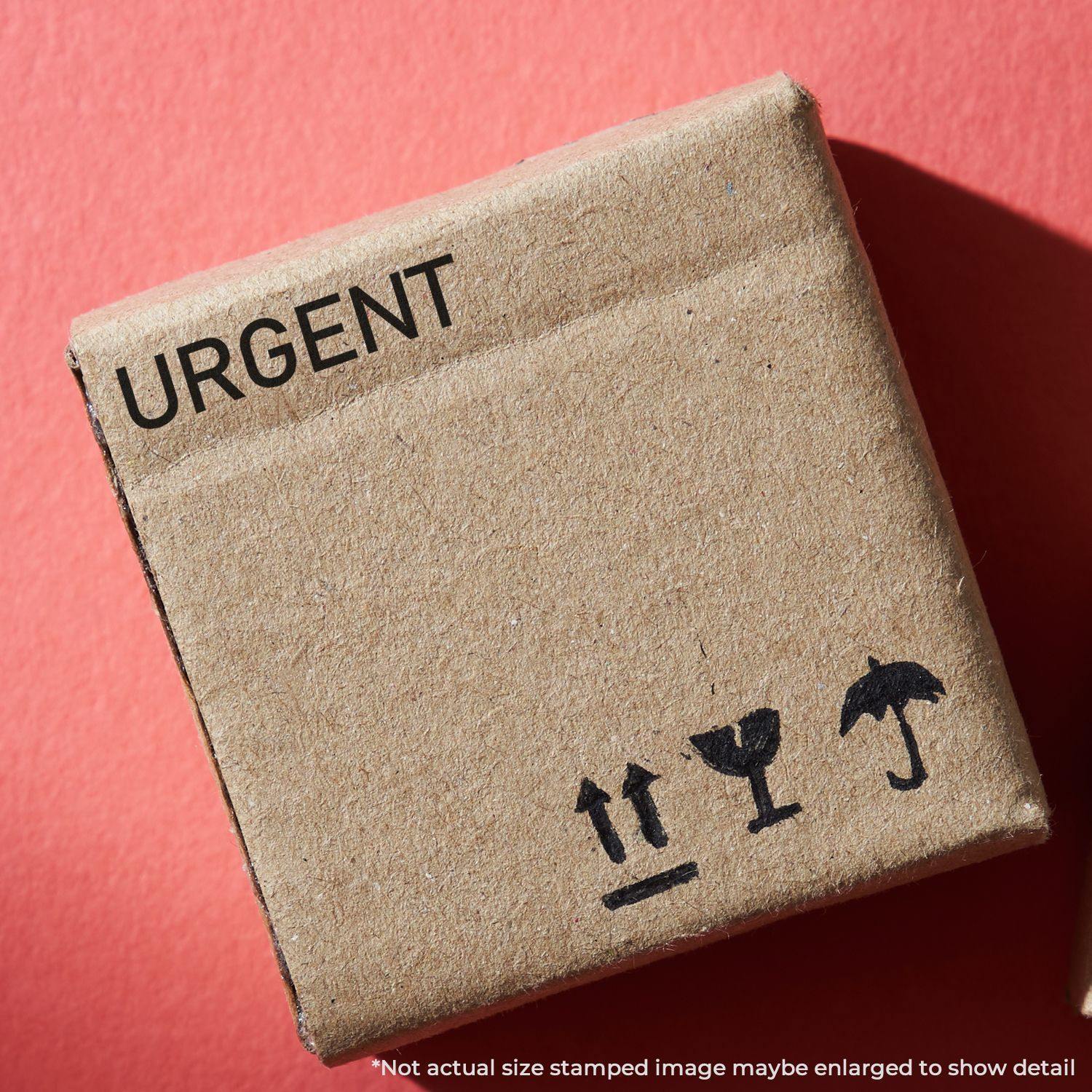 Narrow Font Urgent Rubber Stamp on a brown cardboard box with shipping symbols, against a red background.