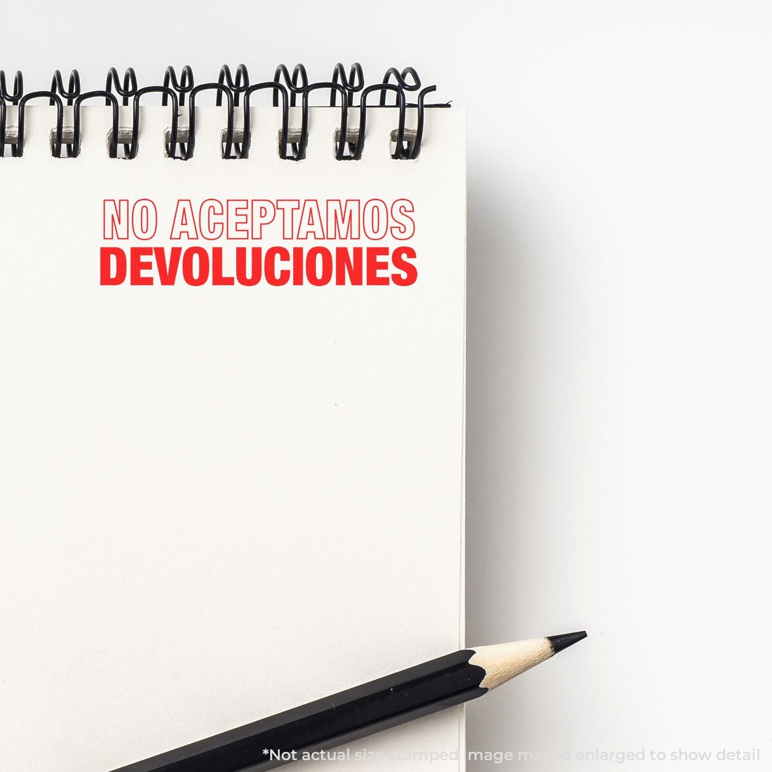 A notebook with a stamped message NO ACEPTAMOS DEVOLUCIONES in red ink using the Self Inking No Aceptamos Devolucions Stamp, next to a pencil.