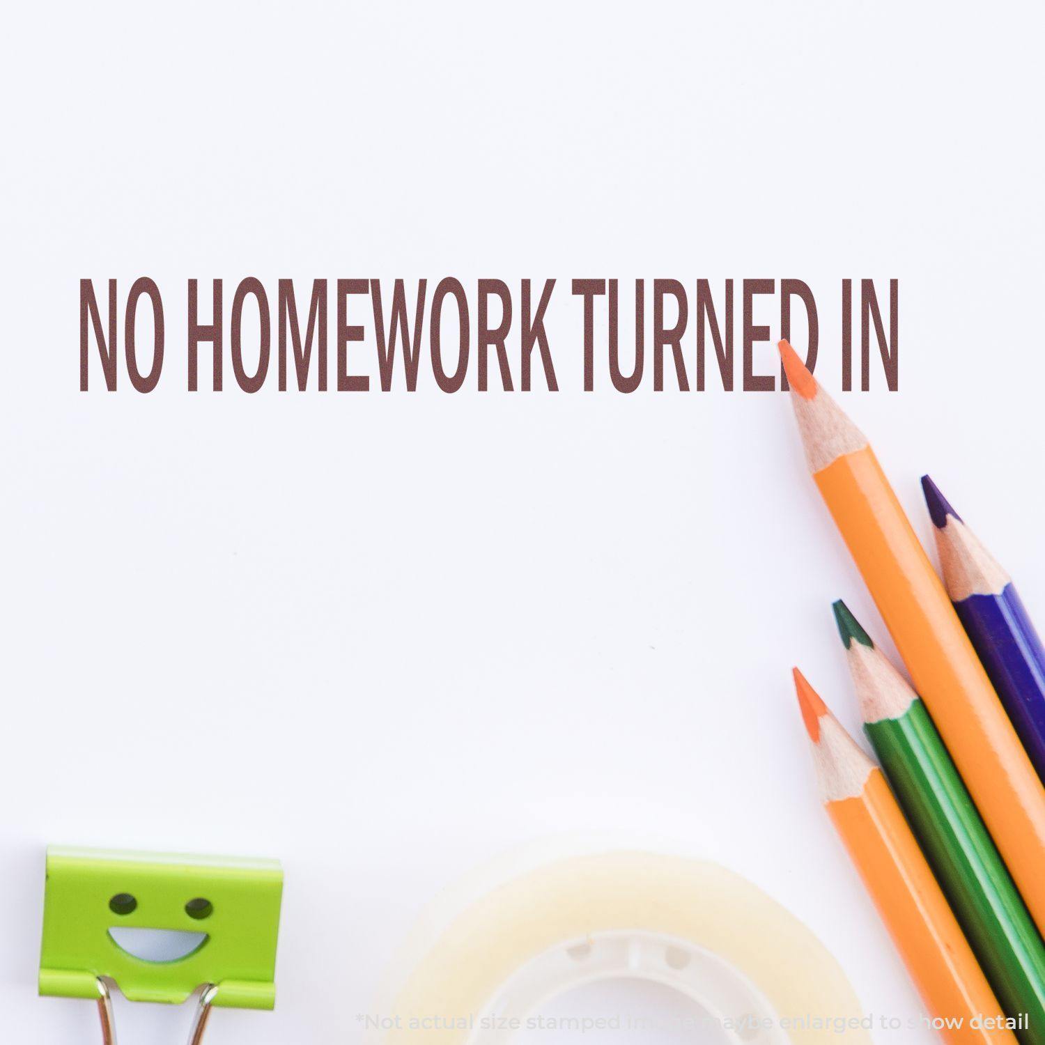 Large No Homework Turned In Rubber Stamp impression on paper with colorful pencils, a smiling paper clip, and tape in the background.