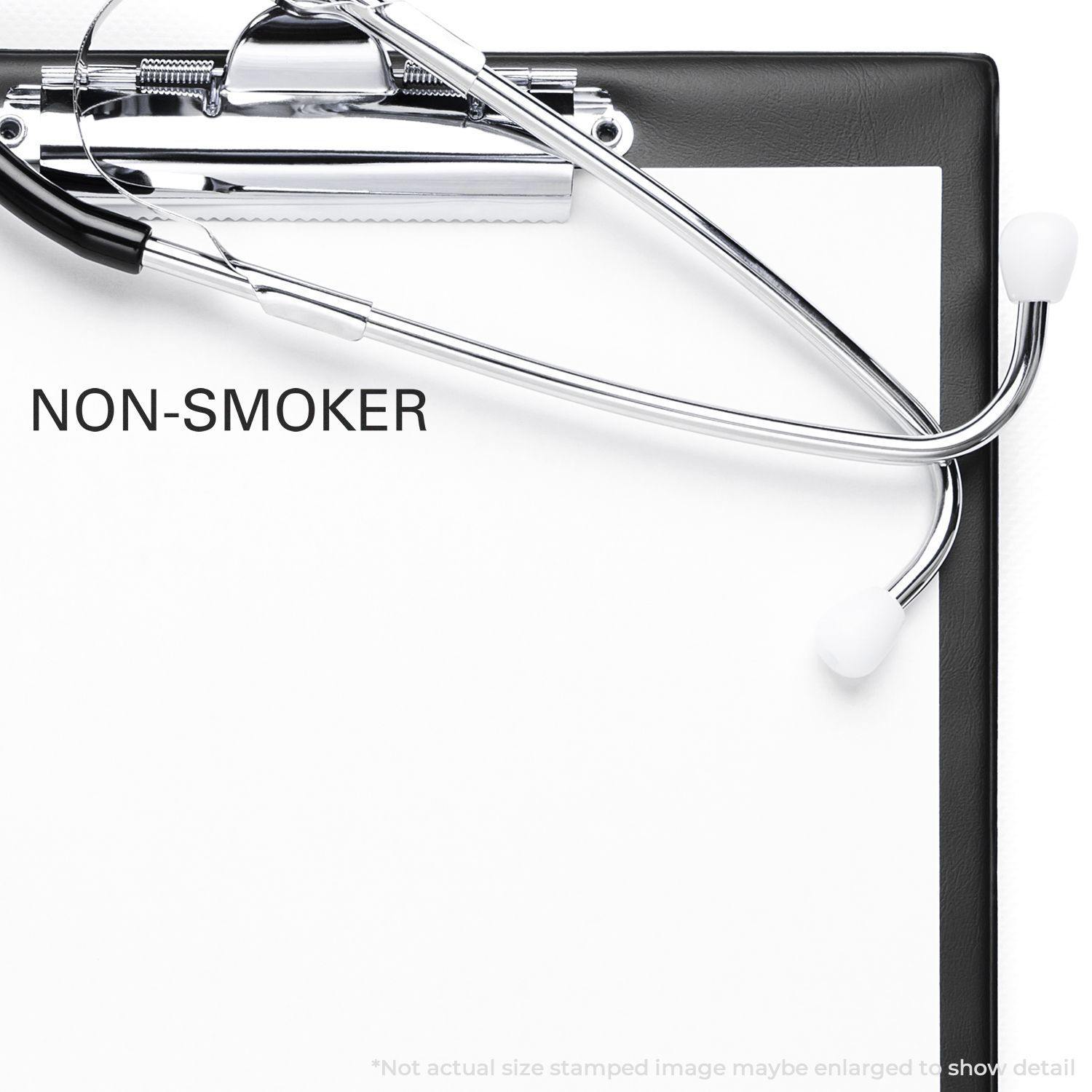 A stock office rubber stamp with a stamped image showing how the text "NON-SMOKER" in a large font is displayed after stamping.