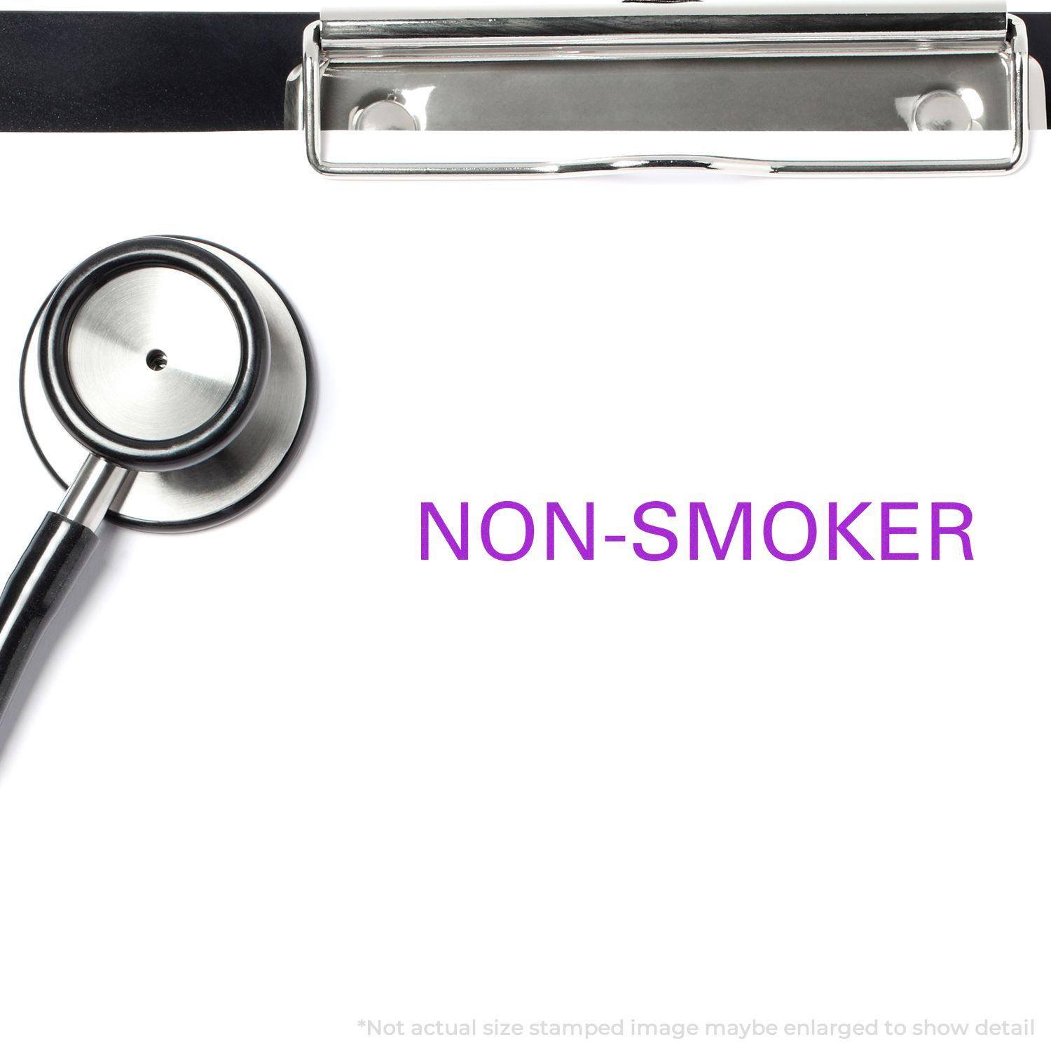 Large Non-Smoker Rubber Stamp in use on a white paper with a stethoscope and clipboard nearby. The stamp reads NON-SMOKER in purple text.