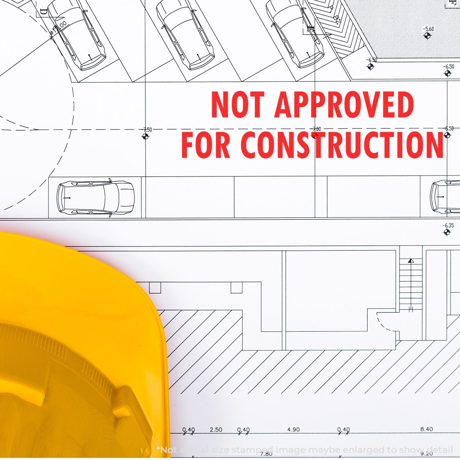 Self Inking Not Approved For Construction Stamp used on a building blueprint, with a yellow hard hat partially visible in the foreground.