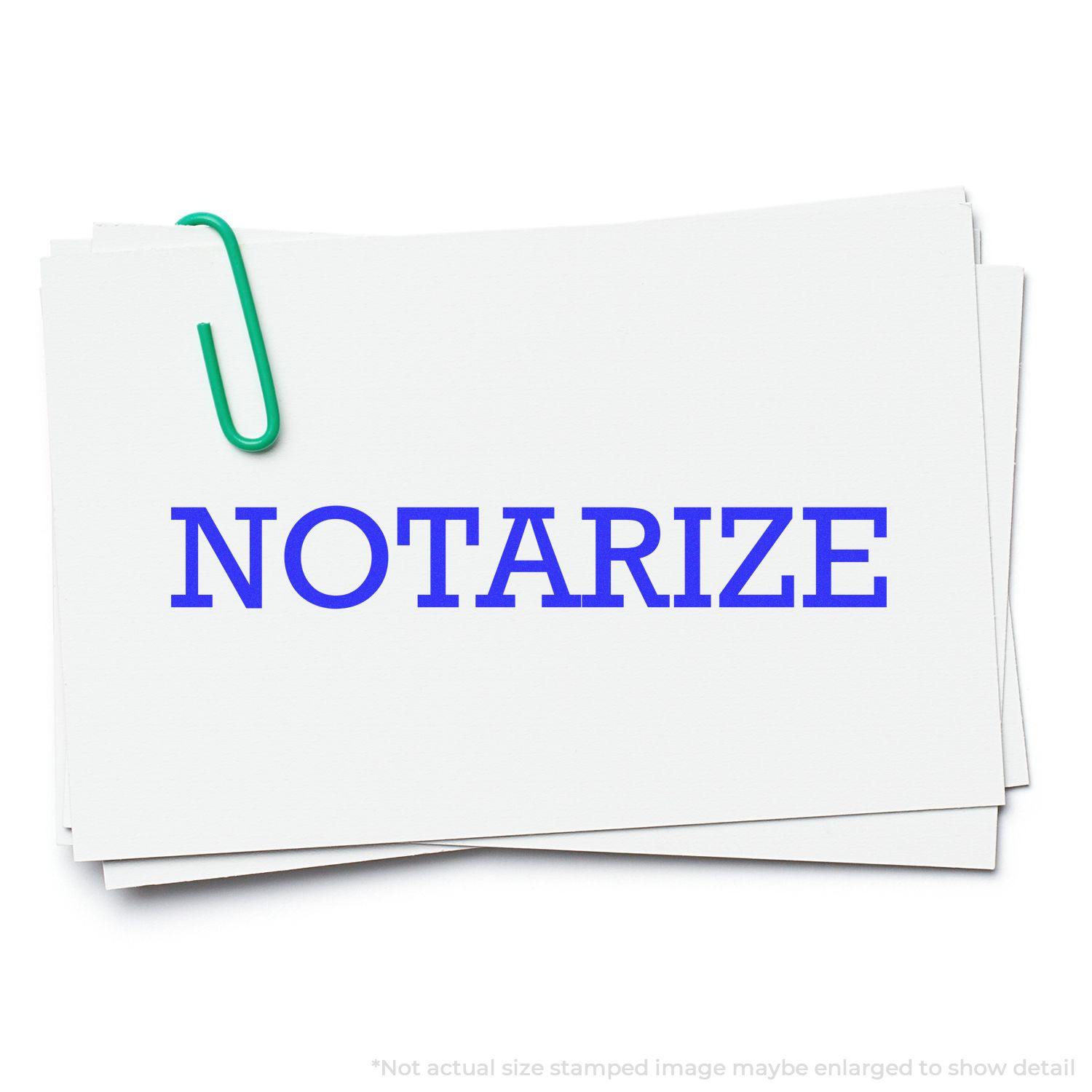 A stack of white cards with the word NOTARIZE stamped in blue using the Large Notarize Rubber Stamp, held together by a green paperclip.