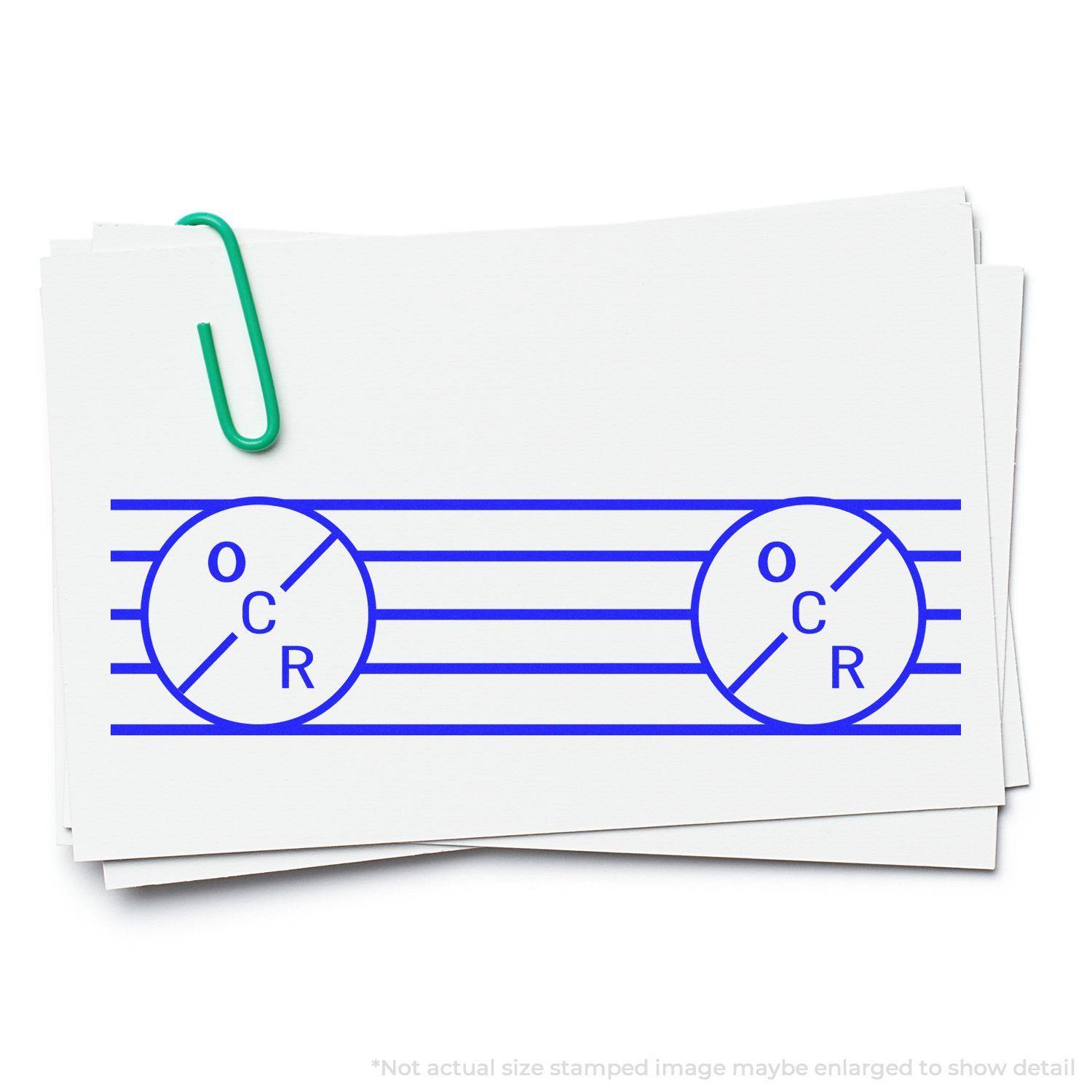 A stack of white cards stamped with blue ink using the Large Self Inking OCR Stamp, secured with a green paperclip.