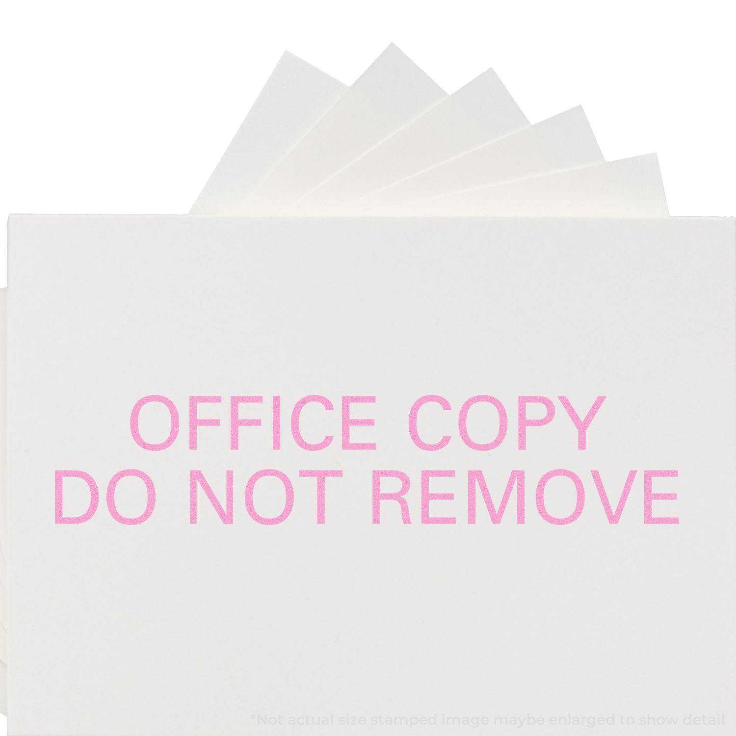 Slim Pre-Inked Office Copy Do Not Remove Stamp in pink ink on white paper, with multiple sheets fanned out behind.