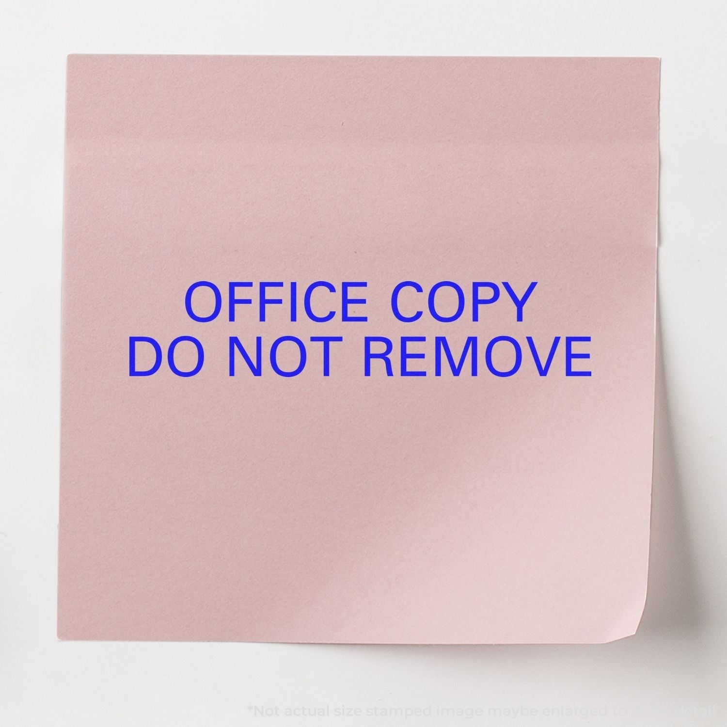 A pink paper stamped with OFFICE COPY DO NOT REMOVE in blue ink using the Self Inking Office Copy Do Not Remove Stamp.