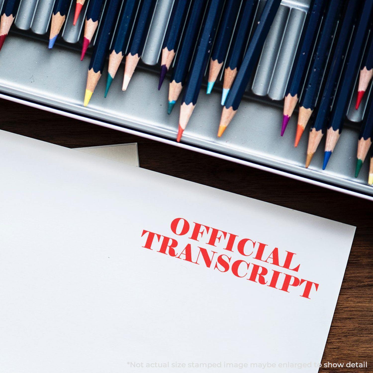 Paper stamped with 'Official Transcript' in red ink, placed next to a box of colored pencils on a wooden surface.