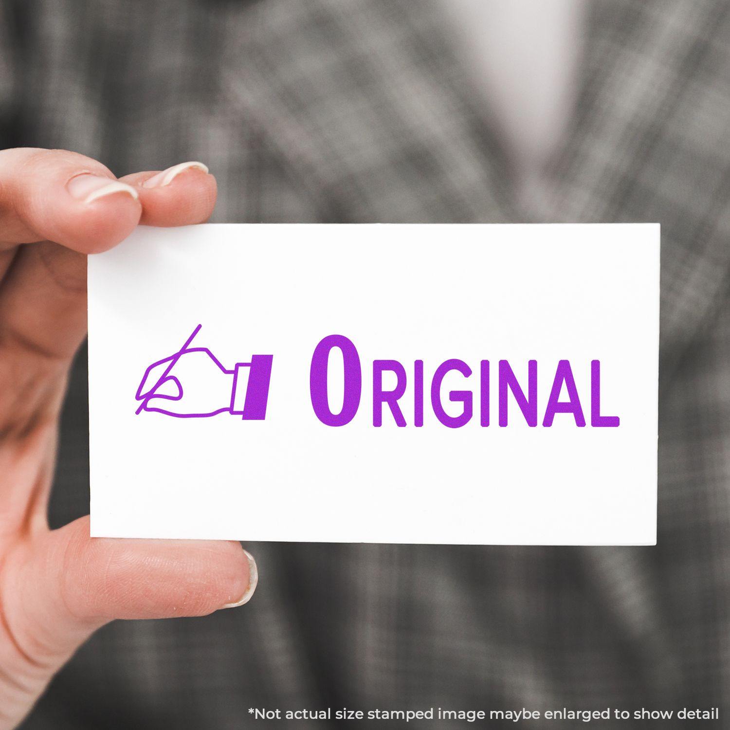 Hand holding a white card with a purple Original with Hand Rubber Stamp imprint, against a blurred plaid background.