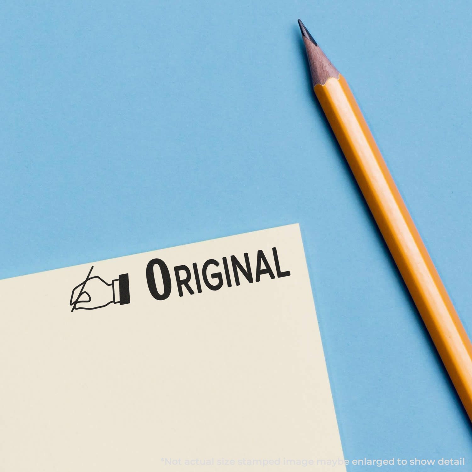 Self Inking Original with Hand Stamp used on a yellow paper next to a sharpened pencil on a blue background.