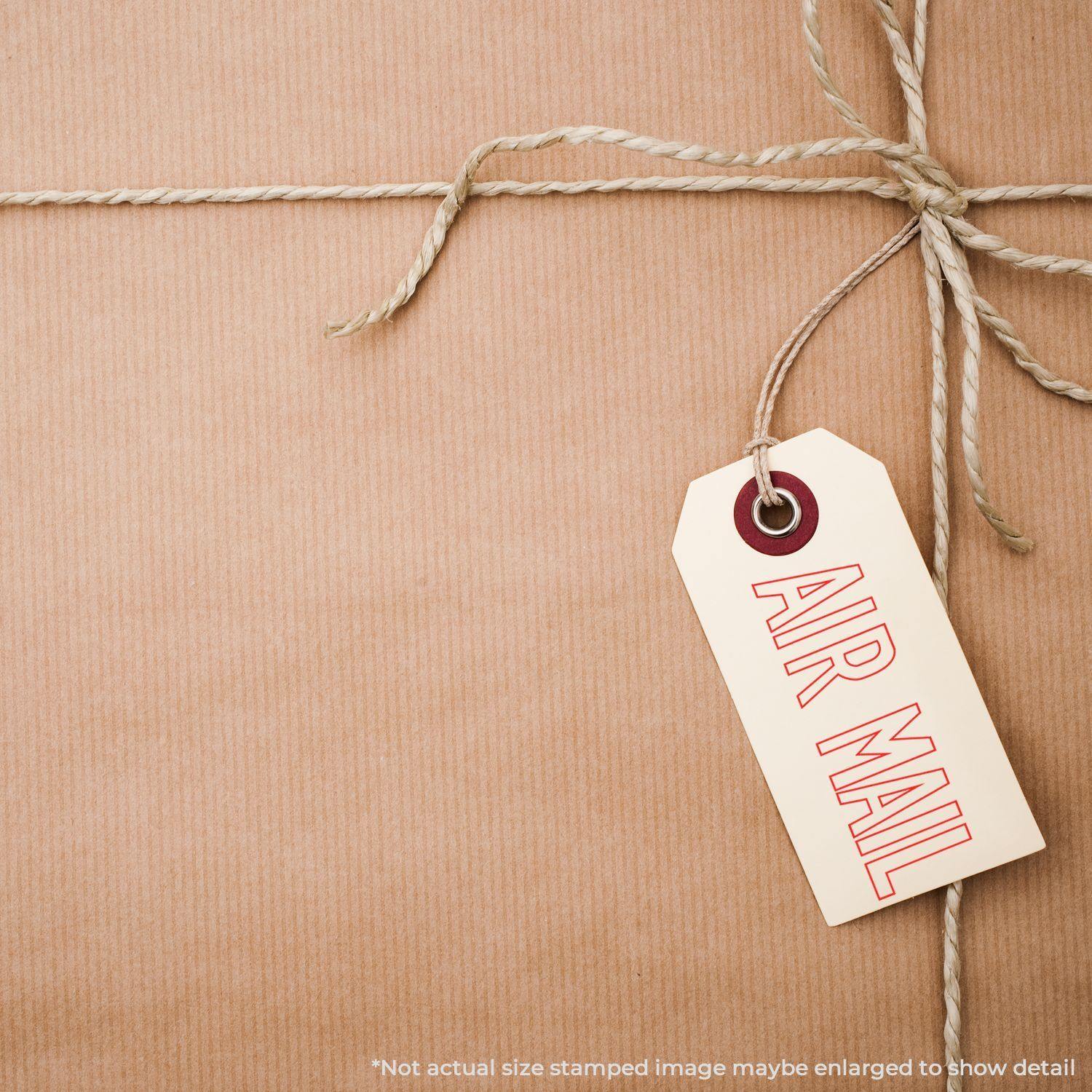 A brown package tied with twine and a tag stamped with AIR MAIL using the Large Outline Air Mail Rubber Stamp.