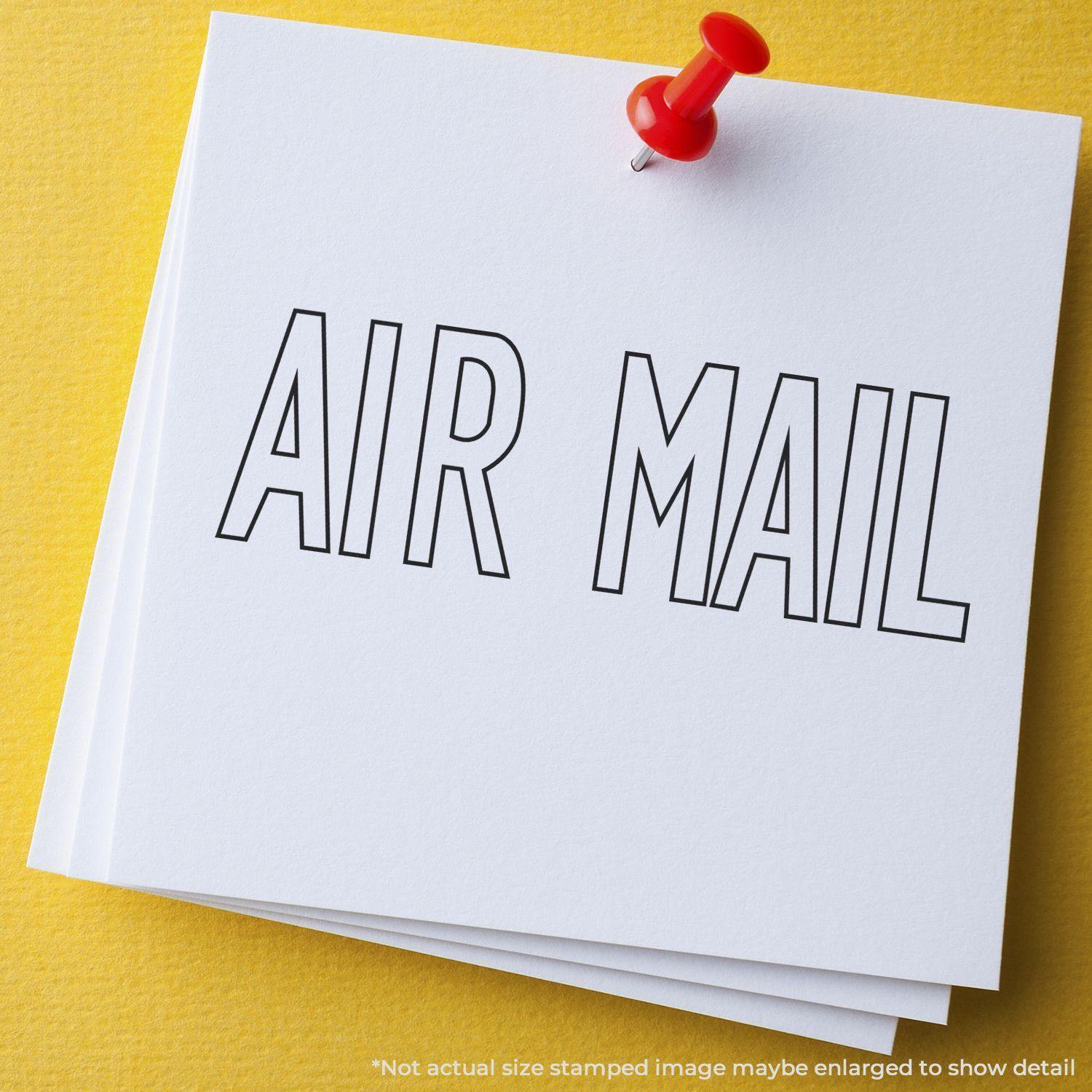 White paper with 'AIR MAIL' stamped in black outline, pinned with a red pushpin on a yellow background. Slim Pre-Inked Outline Air Mail Stamp.