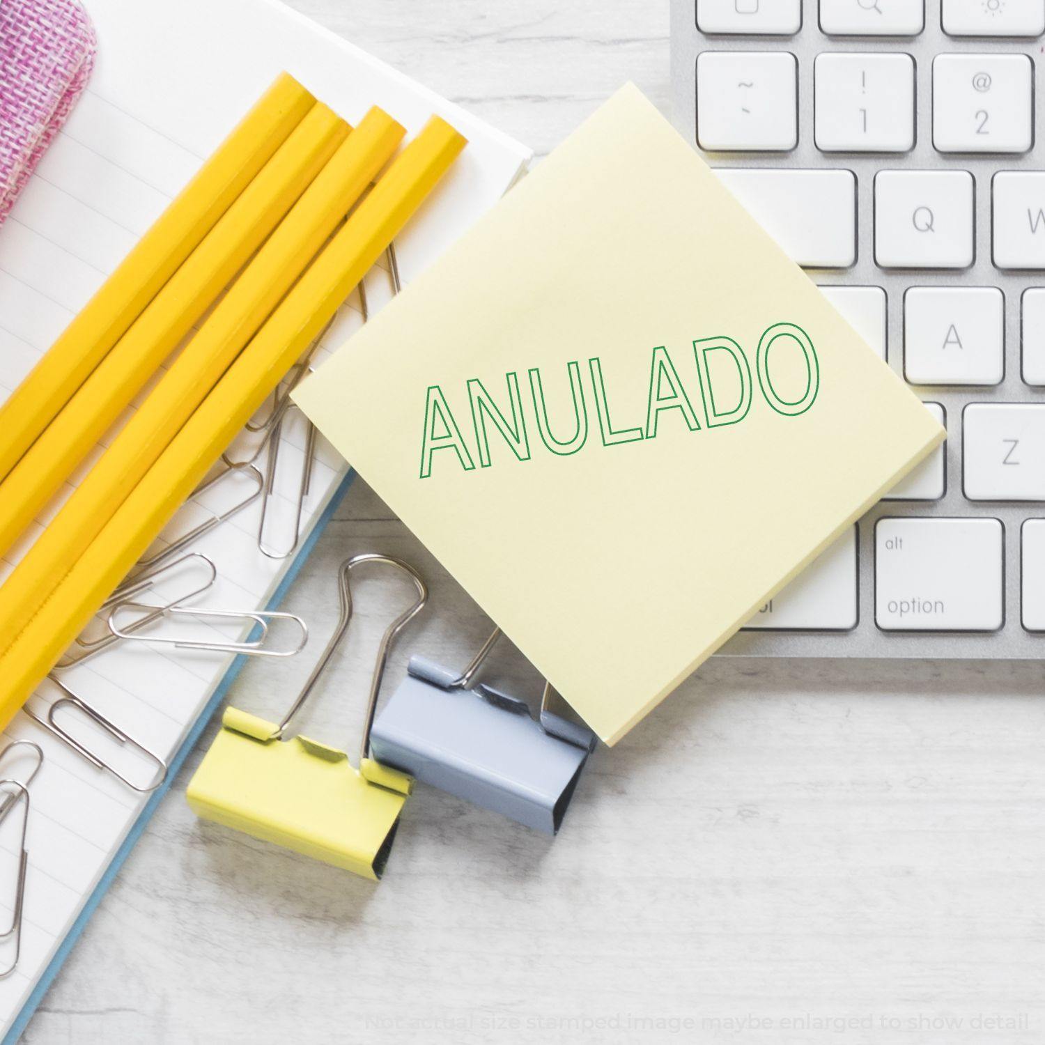 Desk with keyboard, paper clips, pencils, and a sticky note stamped with 'Outline Anulado Rubber Stamp' in green.