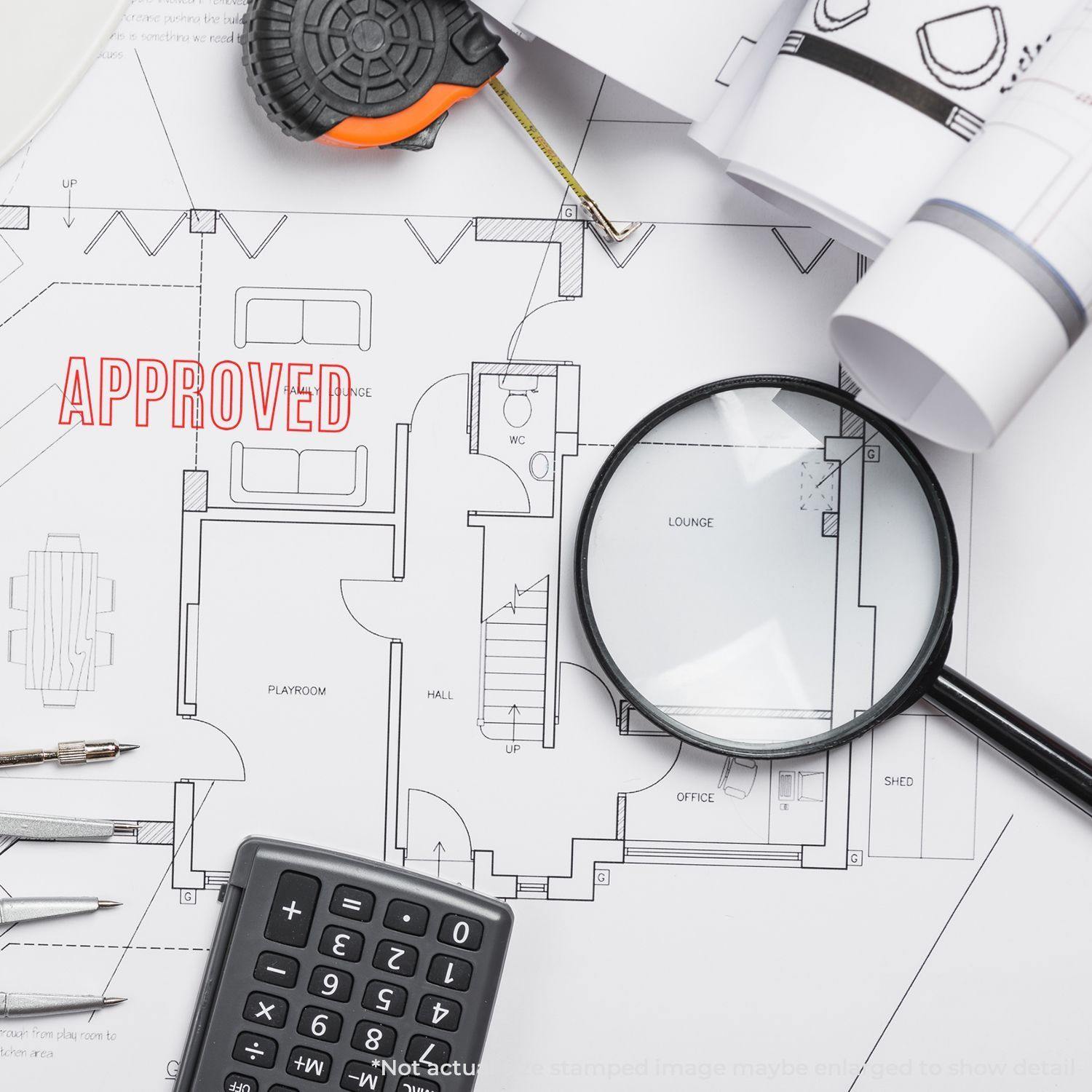 A Large Self Inking Outline Approved Stamp marks APPROVED in red on an architectural blueprint, surrounded by office tools.