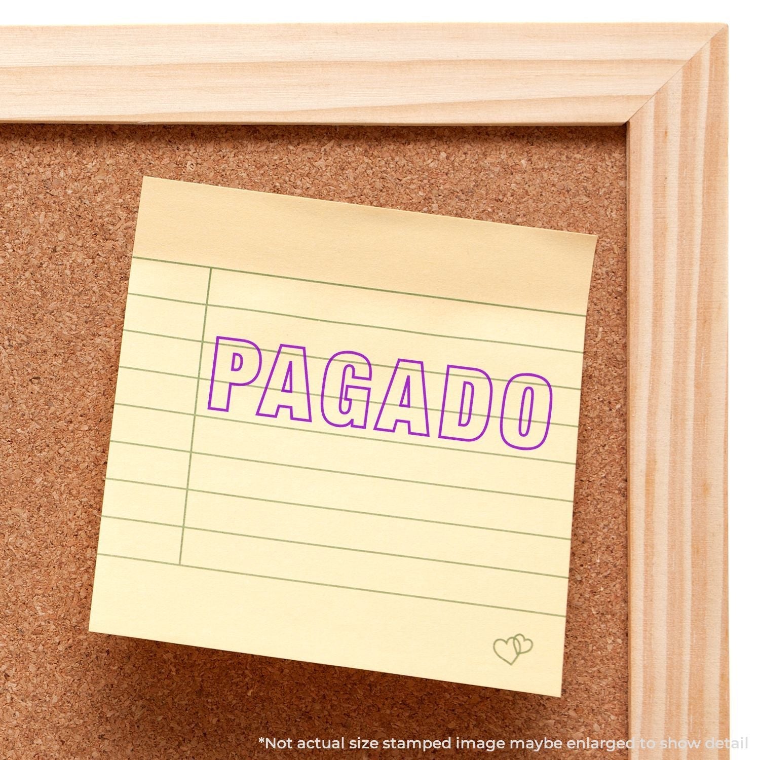 Yellow sticky note on corkboard stamped with PAGADO in purple using the Self Inking Outline Pagado Stamp.