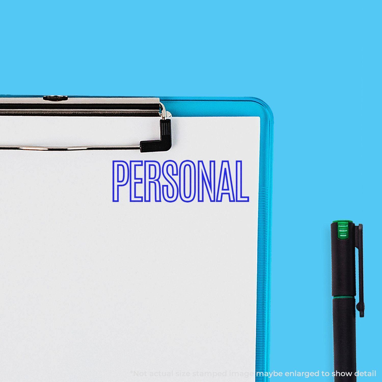 Slim Pre-Inked Outline Personal Stamp used on white paper with the word PERSONAL in blue, next to a black pen on a blue background.