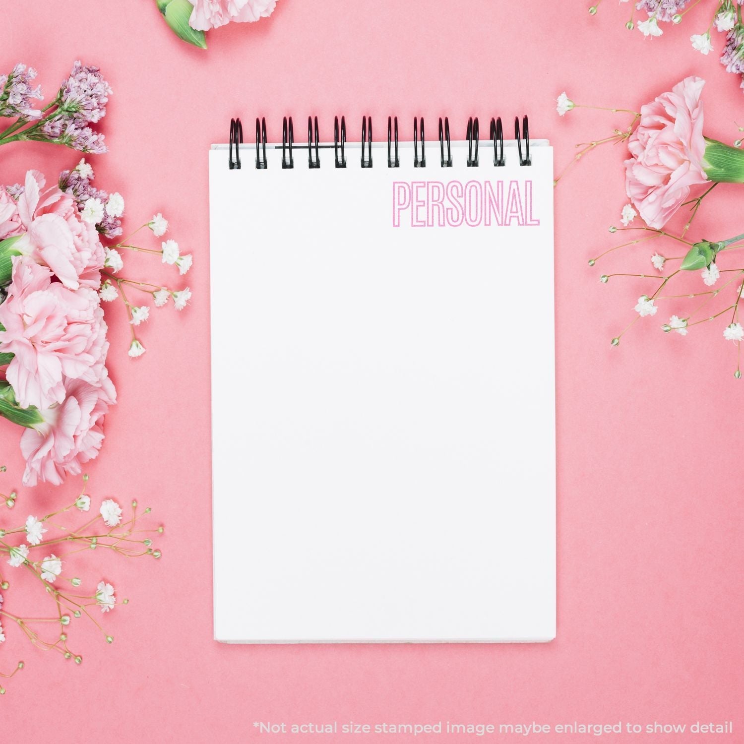 A Self Inking Outline Personal Stamp marks PERSONAL in pink on a white notepad, surrounded by pink and white flowers on a pink background.