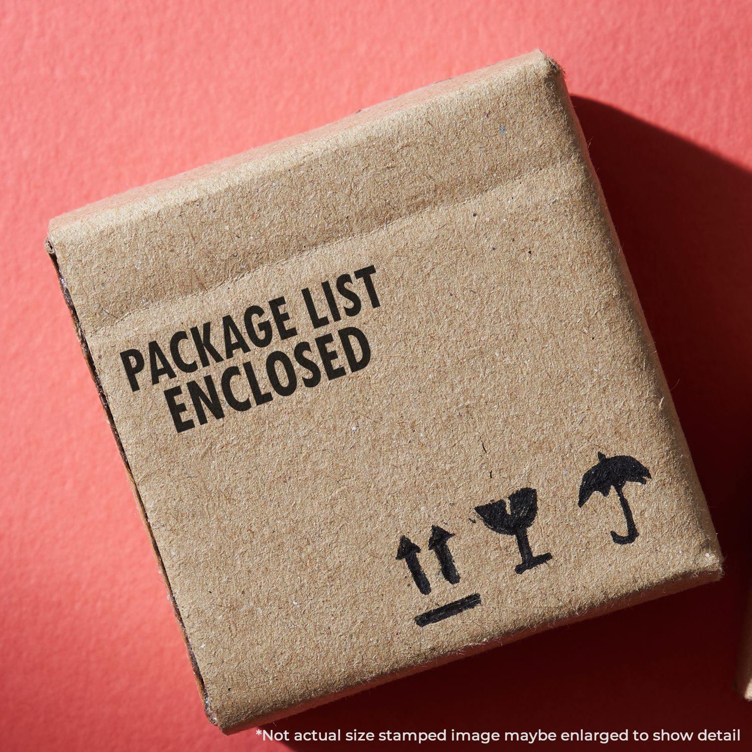 Cardboard box stamped with PACKAGE LIST ENCLOSED using the Large Package List Enclosed Rubber Stamp, placed on a red surface.