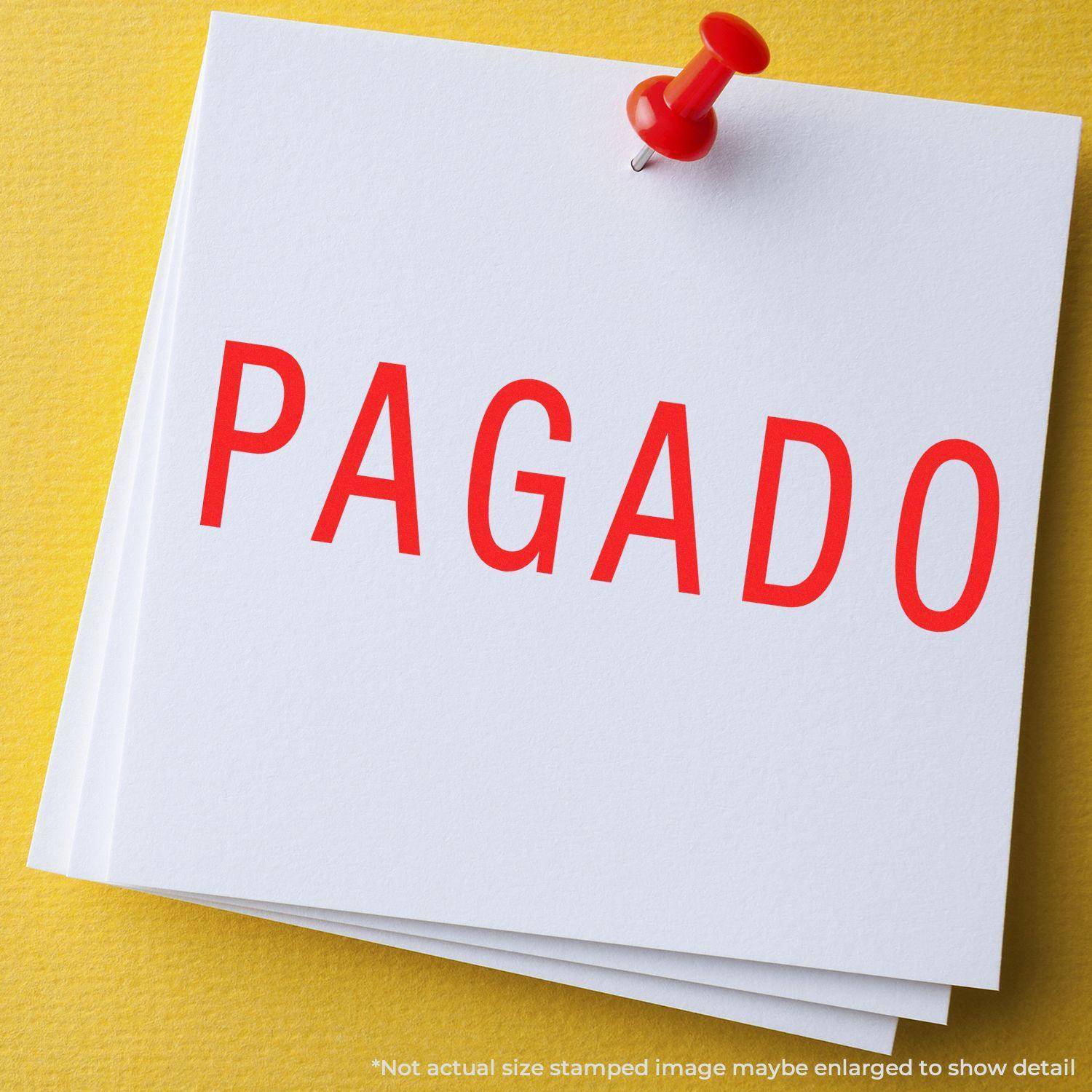 A red PAGADO stamp impression on white paper pinned with a red pushpin. Product: Large Pagado Rubber Stamp.