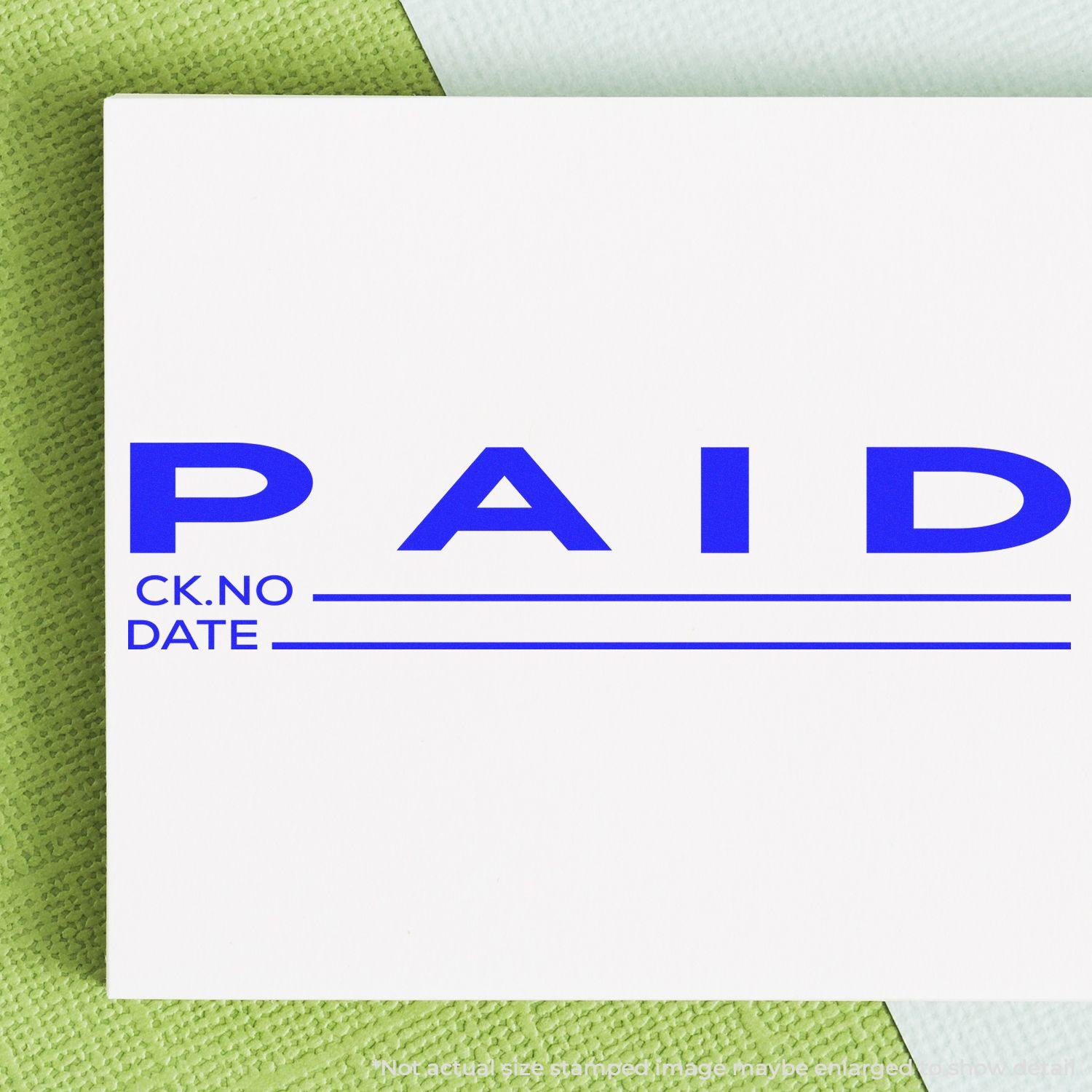 A stock office rubber stamp with a stamped image showing how the text "PAID" in a large font with space where you can write down both the check number and the date is displayed after stamping.