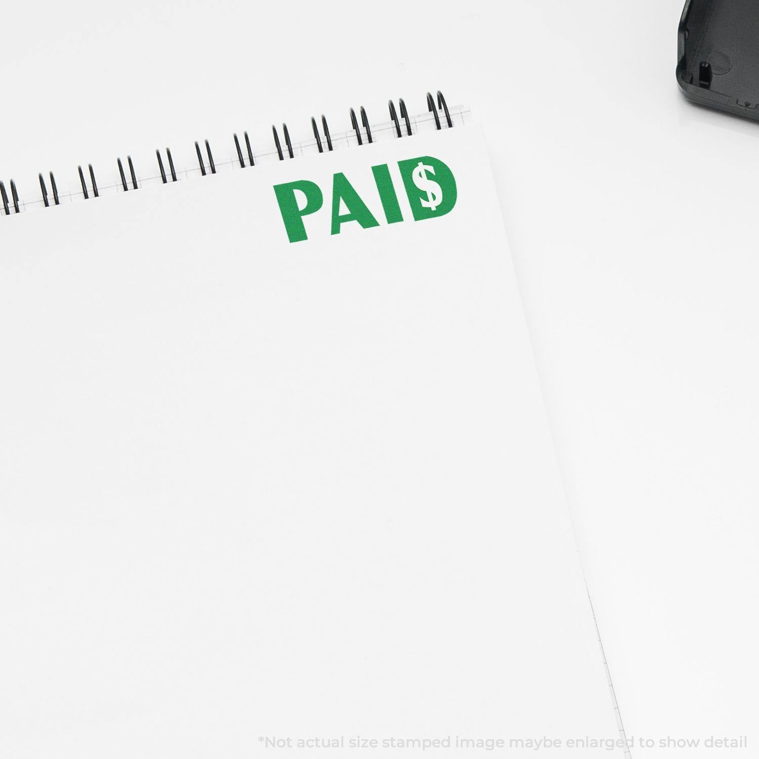 A notebook with a green PAID stamp featuring a dollar sign, created using the Large Paid with Dollar Sign Rubber Stamp.