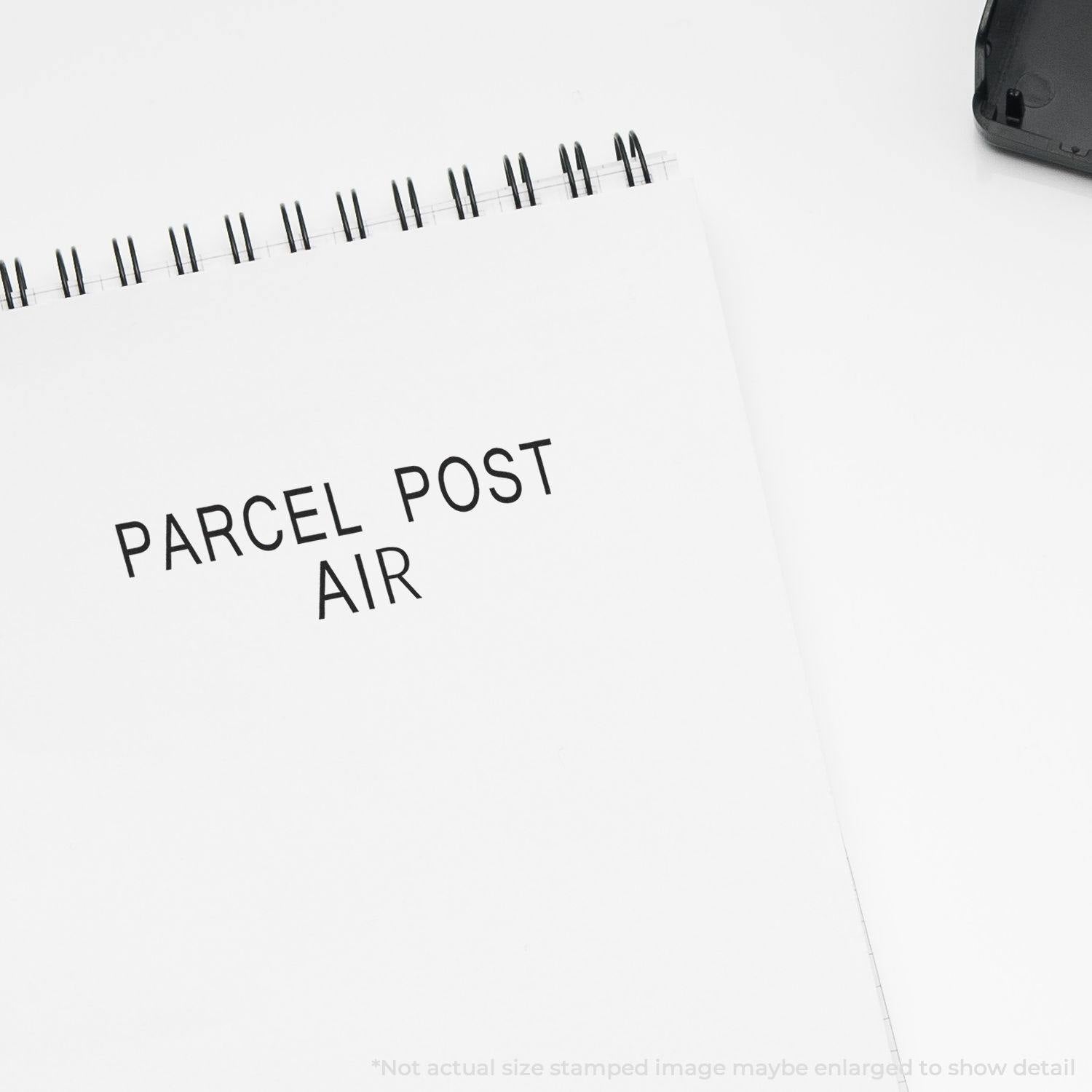 A Large Parcel Post Air Rubber Stamp imprint on a white notepad, with the stamp partially visible in the top right corner.