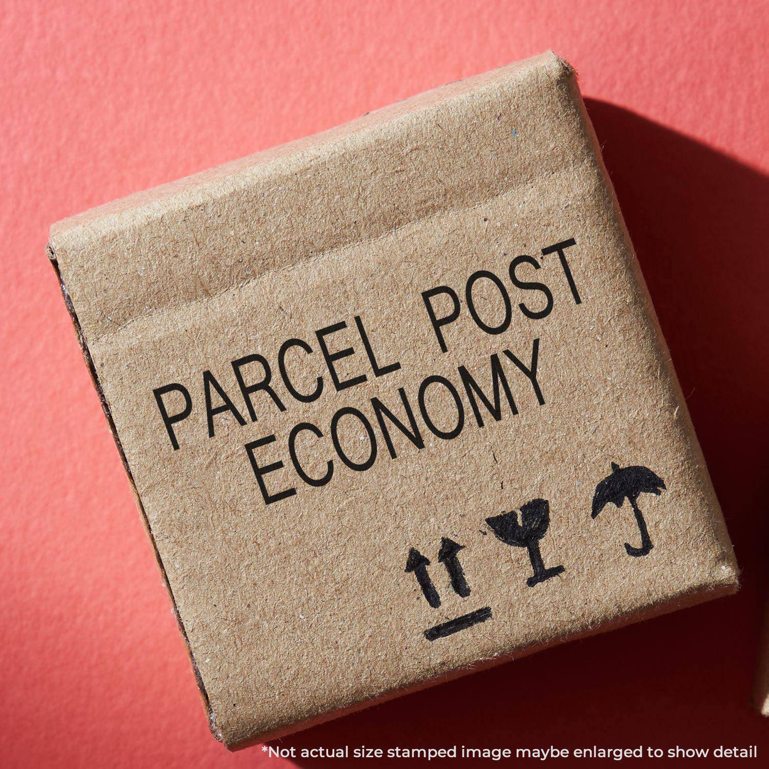 A cardboard box stamped with PARCEL POST ECONOMY using the Large Parcel Post Economy Rubber Stamp on a red background.