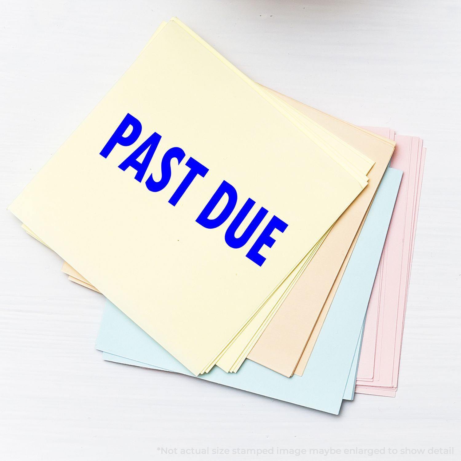 A stack of pastel-colored papers stamped with PAST DUE in blue using the Large Self Inking Past Due Stamp, placed on a white surface.