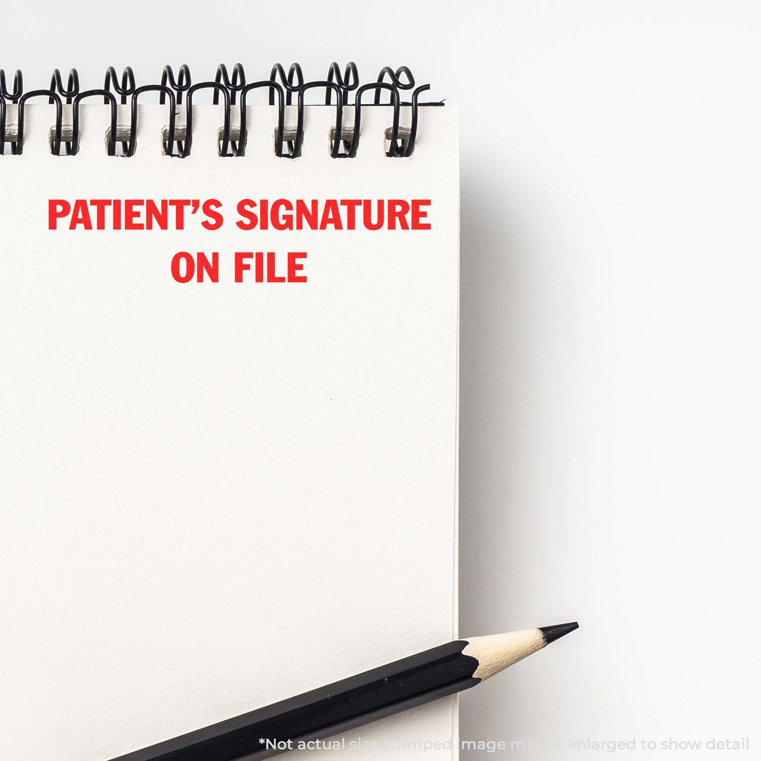 Large Pre-Inked Patient's Signature on File Stamp in red ink on a white notepad with a black pencil beside it.