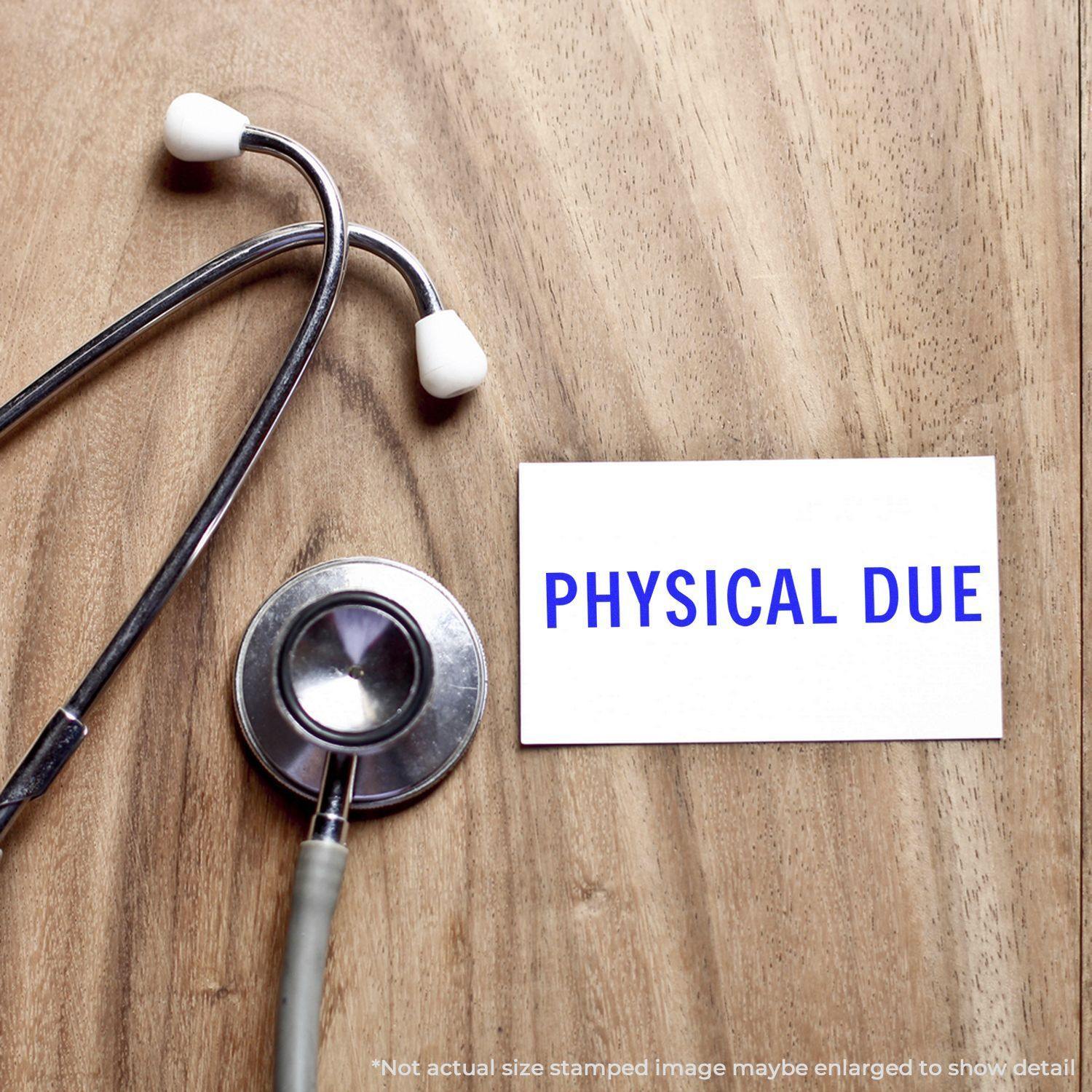 Large Self Inking Physical Due Stamp on a white card next to a stethoscope on a wooden surface.