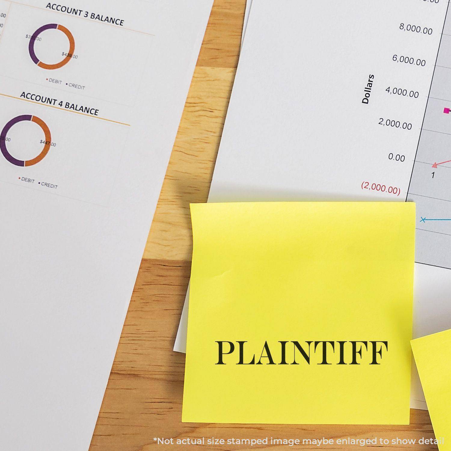 Large Plaintiff Rubber Stamp used on a yellow sticky note, placed on a desk with financial documents and charts in the background.