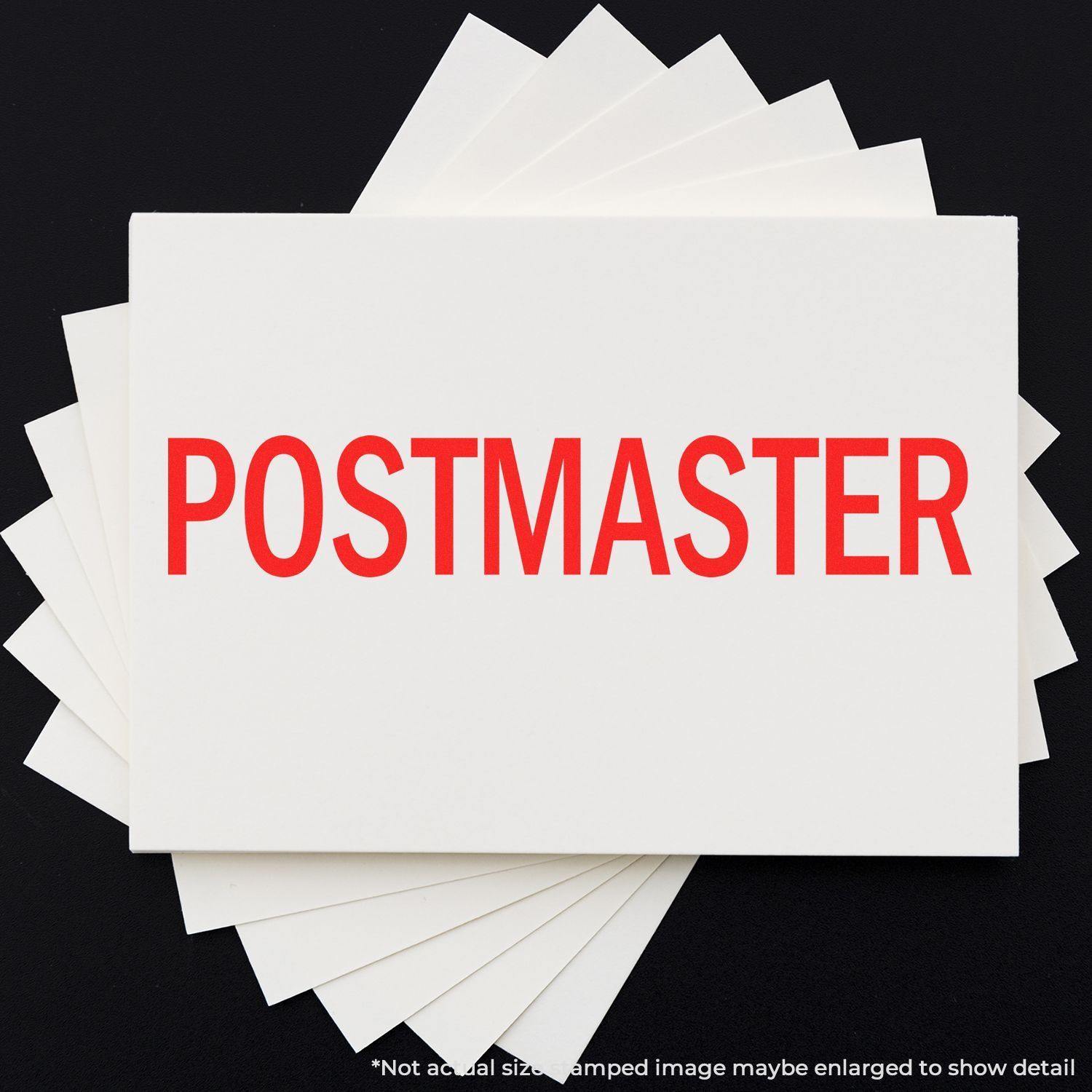 Large Postmaster Rubber Stamp in red ink on white paper, with multiple sheets fanned out underneath.