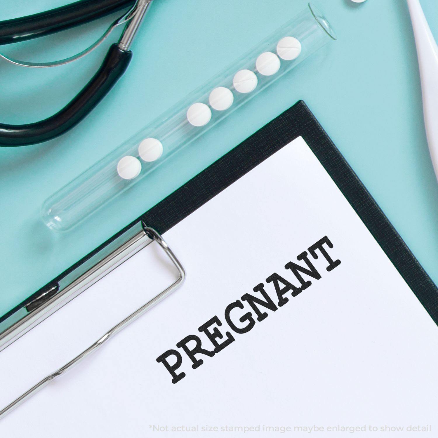 Clipboard with PREGNANT stamped on paper using Large Pregnant Rubber Stamp, stethoscope, and test tube with pills on a light blue background.