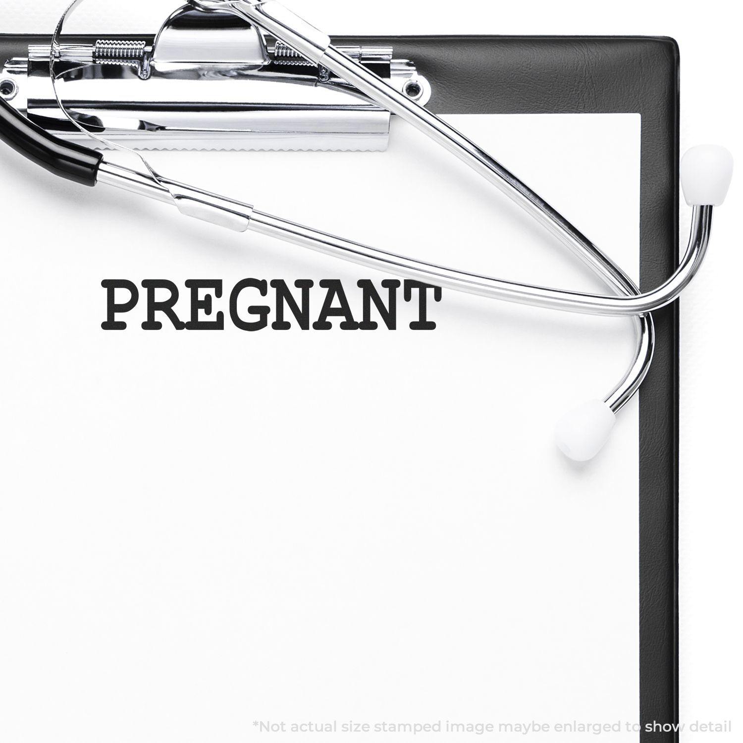 Clipboard with PREGNANT stamped on paper using the Large Self Inking Pregnant Stamp, with a stethoscope placed on top.