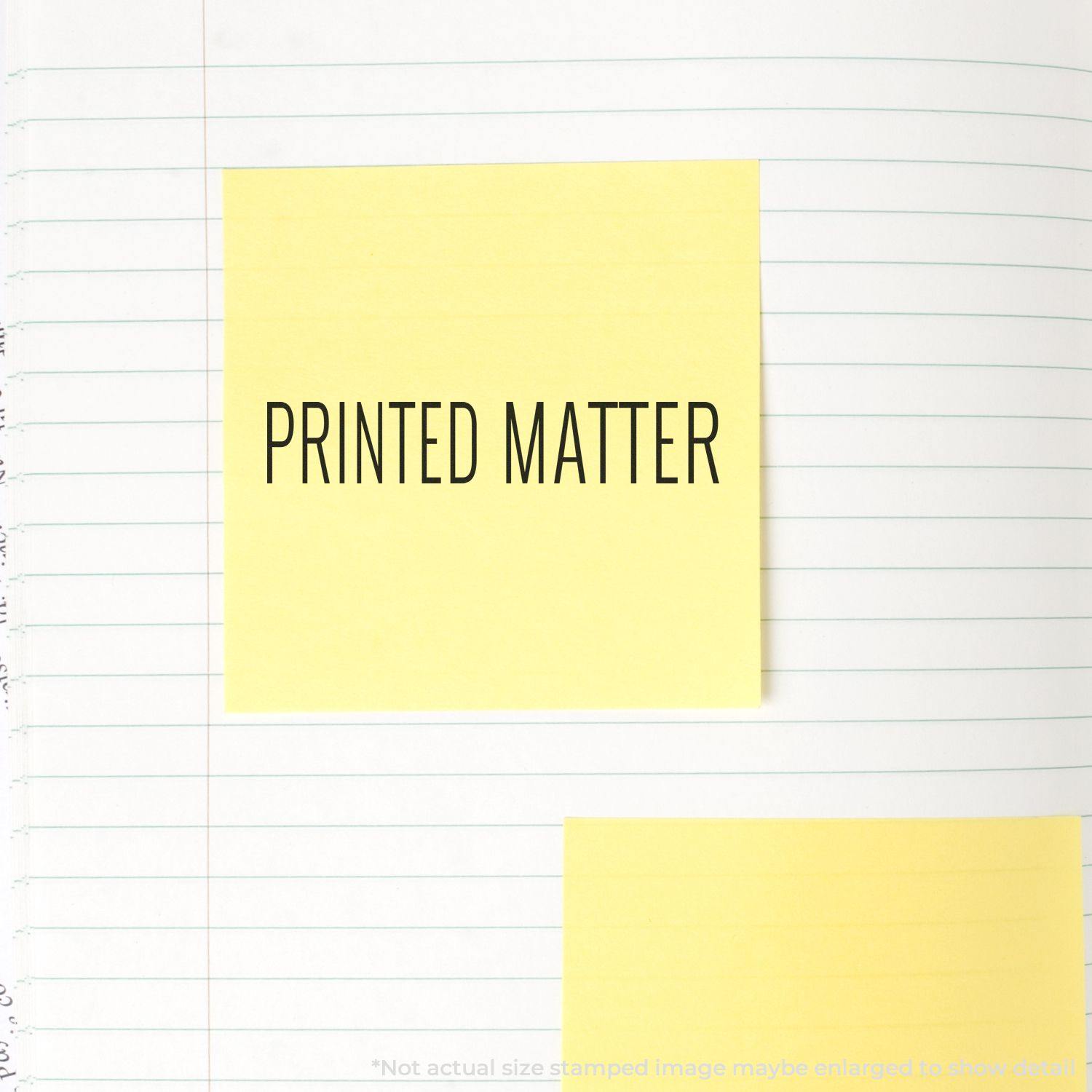 Large Pre-Inked Printed Matter Stamp used on a yellow sticky note placed on a lined notebook page.